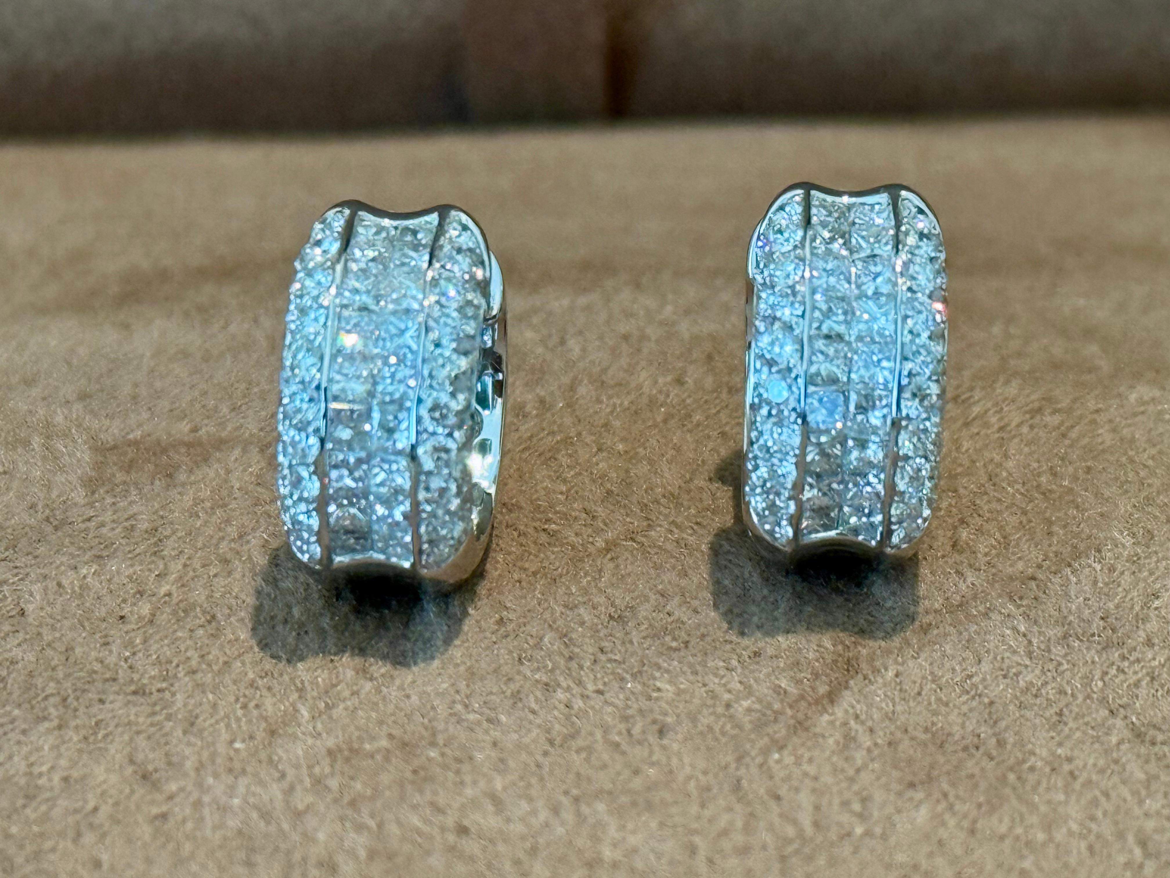 Questi deliziosi orecchini a cerchio sono costituiti da una combinazione vincente di diamanti rotondi taglio brillante incastonati.  alternati a sezioni di diamanti taglio princess per un bellissimo gioco di riflessi! Realizzati in oro bianco 18 K.,