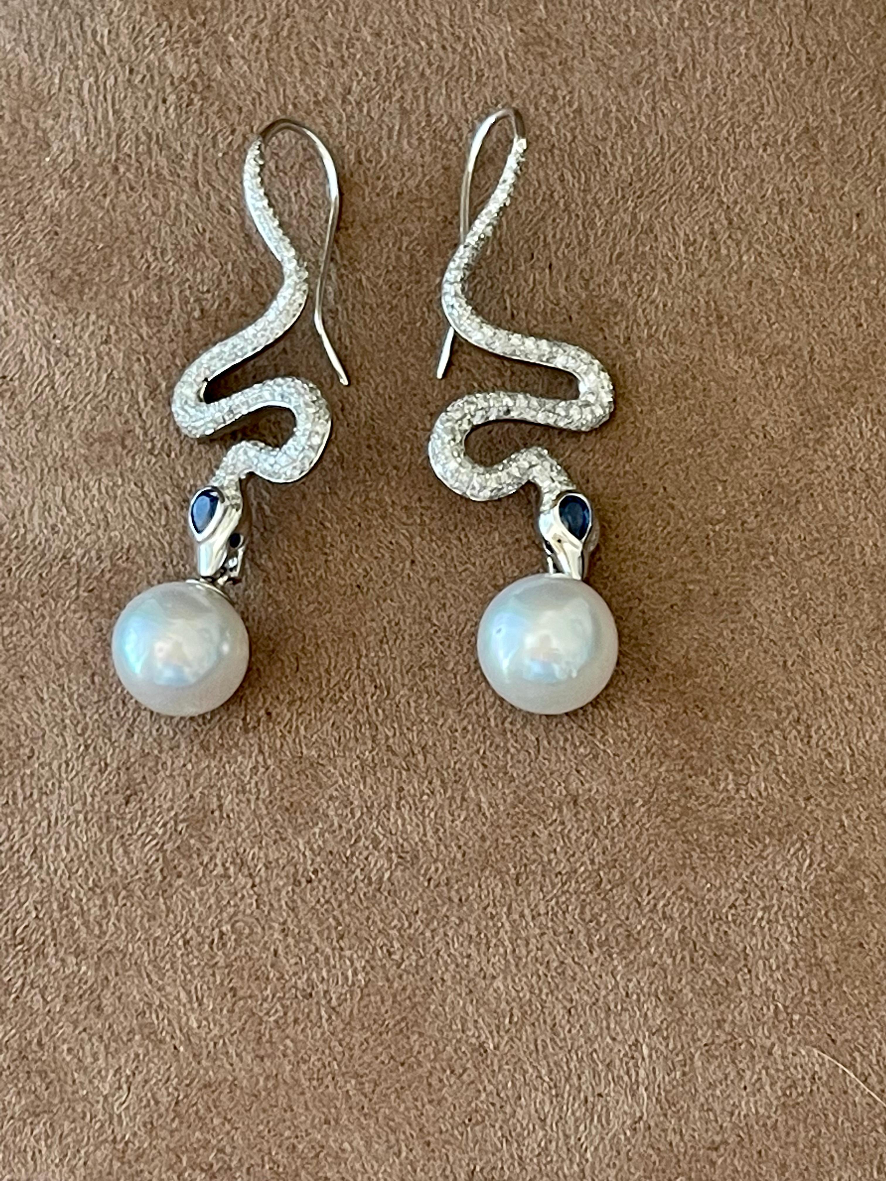 A pair of unique 18 K white Gold  Snake earrings featuring 2 fine South Sea Pearls (1.04 mm), 328 brilliant cut Diamonds weighing 1.31 ct and 6 blue Sapphires weighing 0.48 ct. Length: 5.30 cm. 
The image of the snake has been used in jewelry for