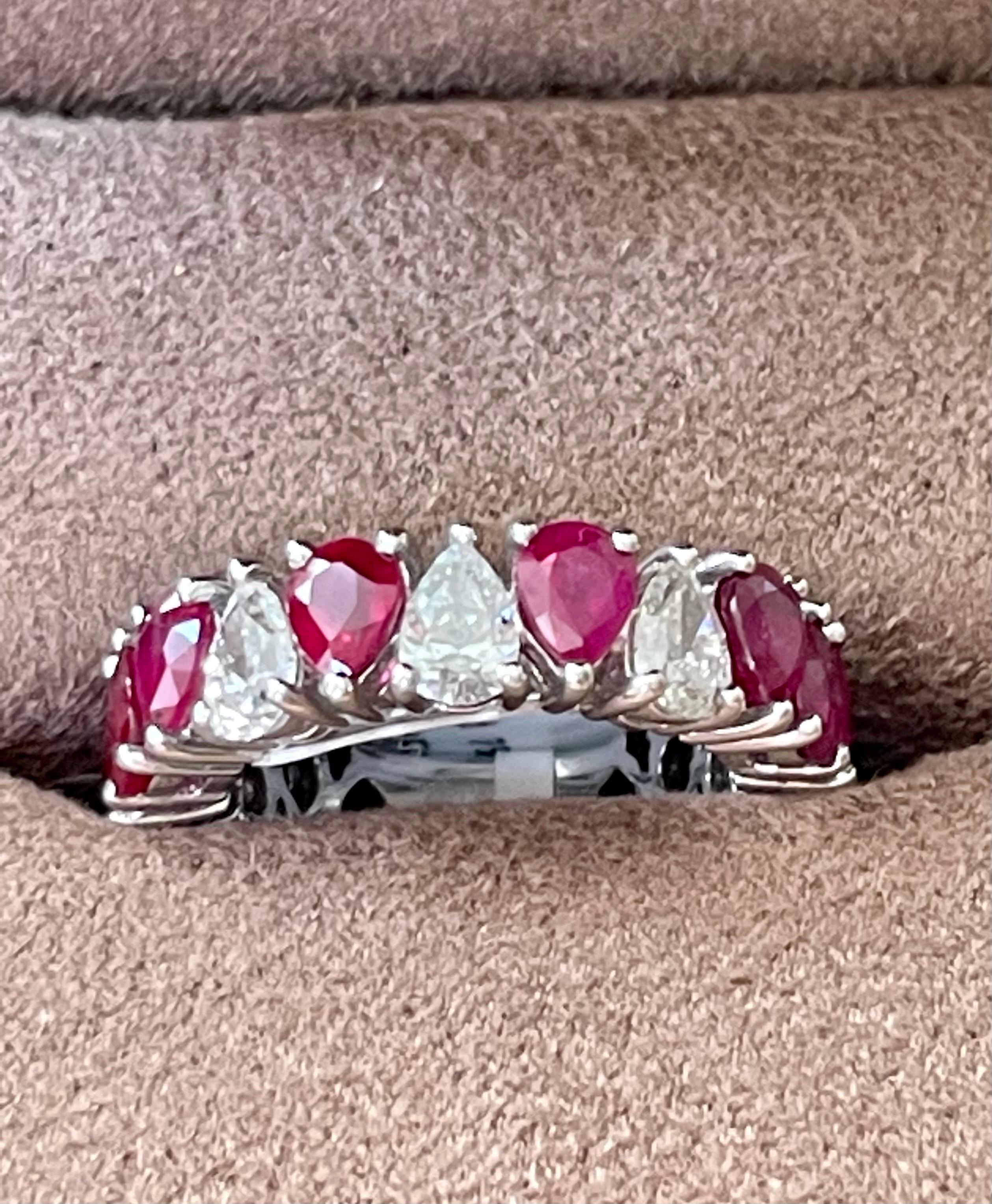 An exquisite find. This 18 K white gold prong set eternity ring features 14 pear shape Rubies with a total weight of 4.99 ct and 3 pear shape DIamonds weiging 0.8 ct, J color, I 1 clarity. Width of ring measures 6 mm at widest point and tapers down