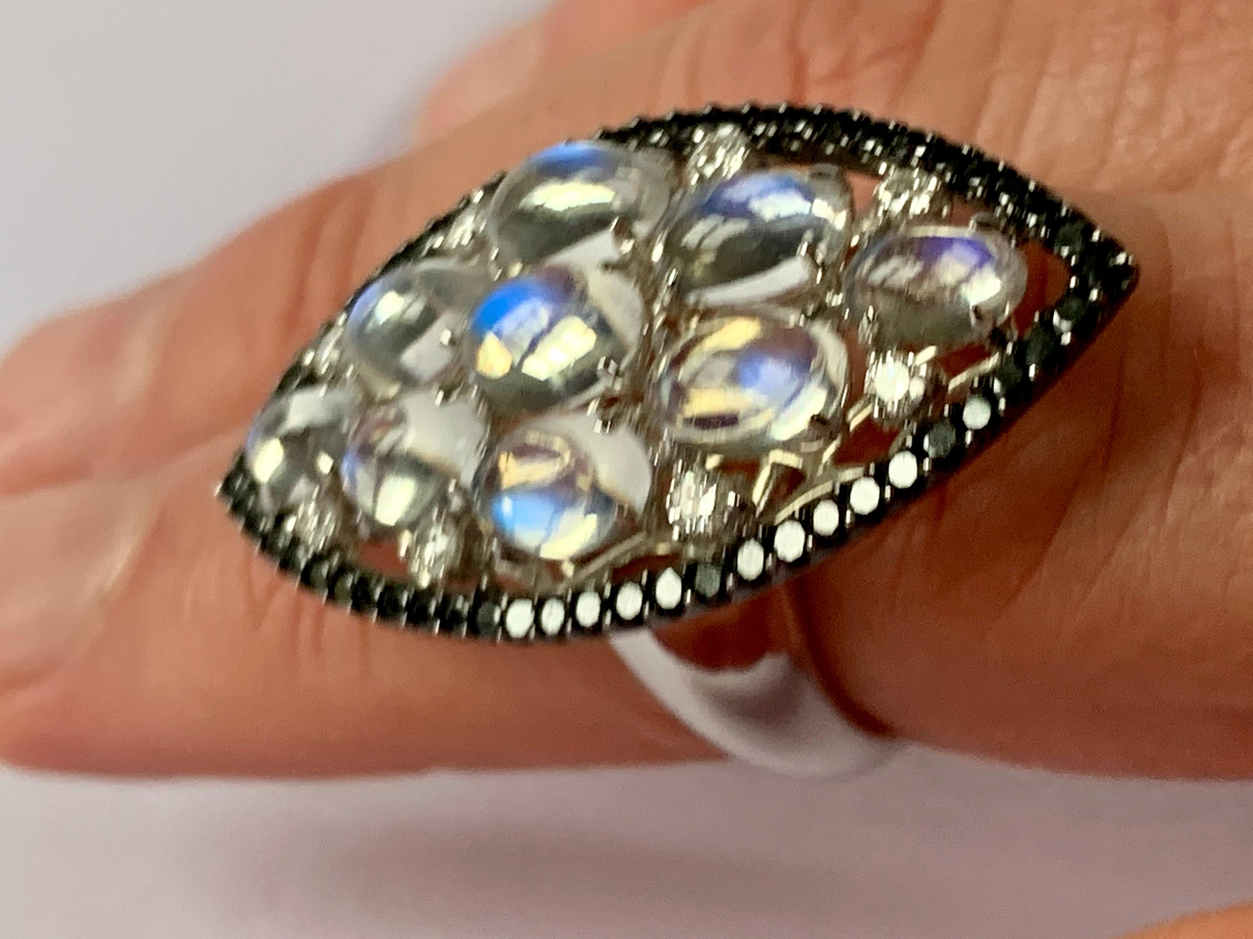 Very unusual 18 K white Gold Cocktail Ring featuring 3 lovely Moonstones Cabochons weighing 6.63 ct surrounded by black Diamonds weighing 0.65 ct in a black rhodium setting. Accentuated by 8 white brilliant cut Diamonds weighing 0.30 ct. 
The