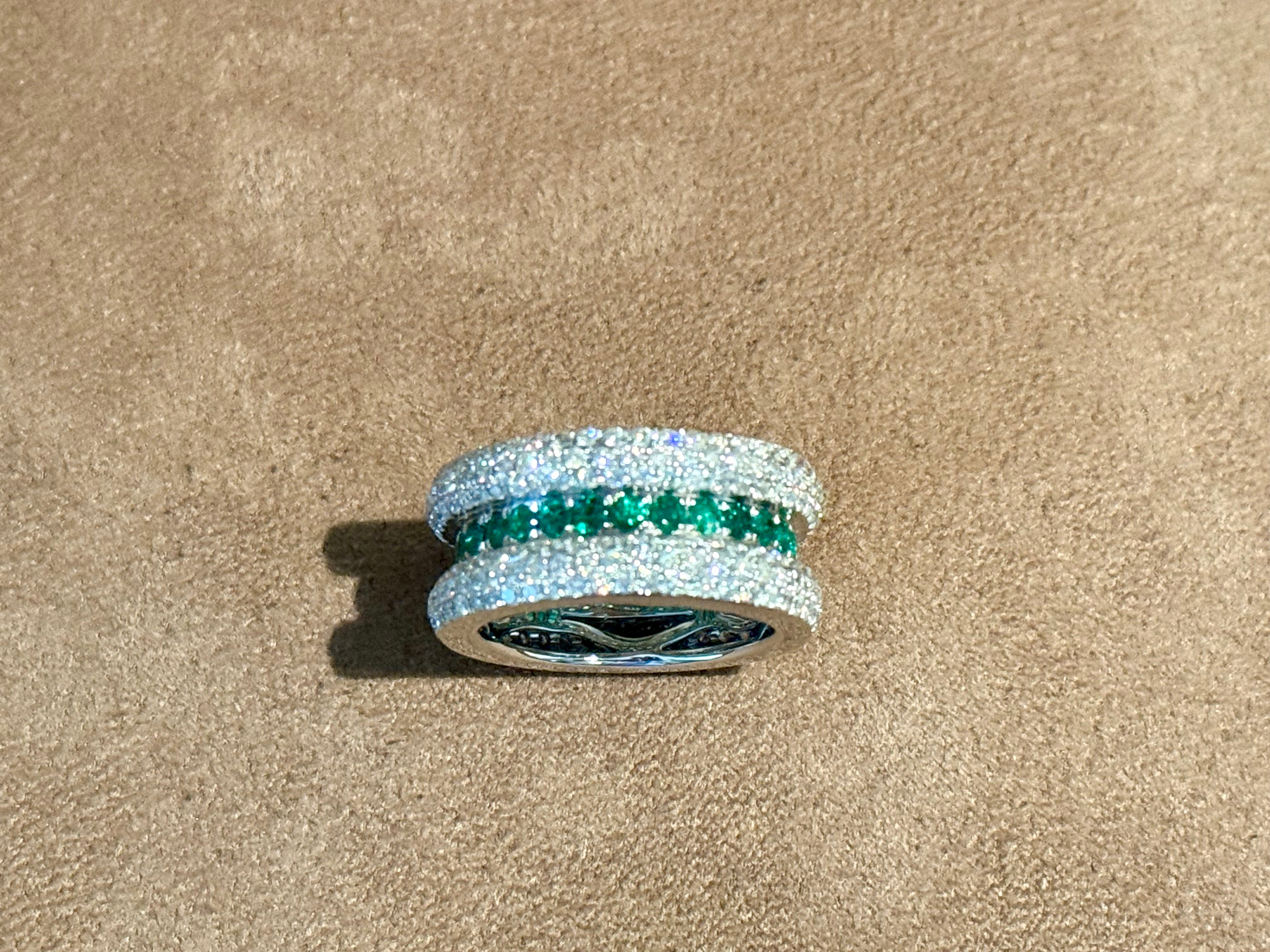 Cette bague sophistiquée en or blanc 18 K est ornée de 27 émeraudes rondes pesant 1,20 ct et de 288 diamants ronds de taille brillant pesant 2,60 ct, de couleur H et de pureté si, dans une monture pavée raffinée. 
La couleur froide de l'or blanc
