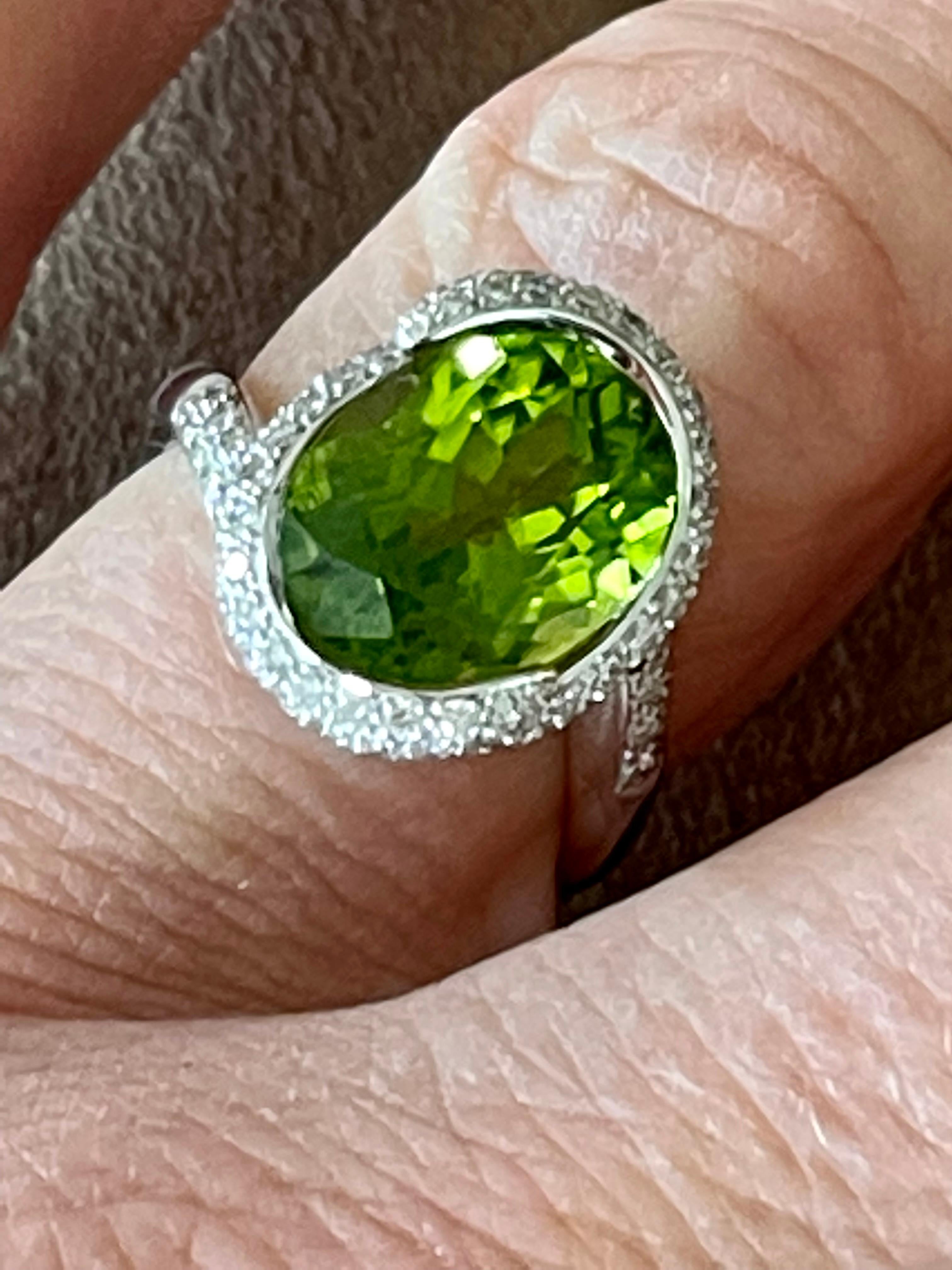 An 18 K whitel Gold Ring that contains a fine oval Peridot weighing 6.65ct and brilliant cut Diamonds weiging 0.89 ct, G color, vs clarity.
The face of the ring measures 1.65 cm tall by 1.32 cm wide. It is stamped with the makers mark and 750. 
The