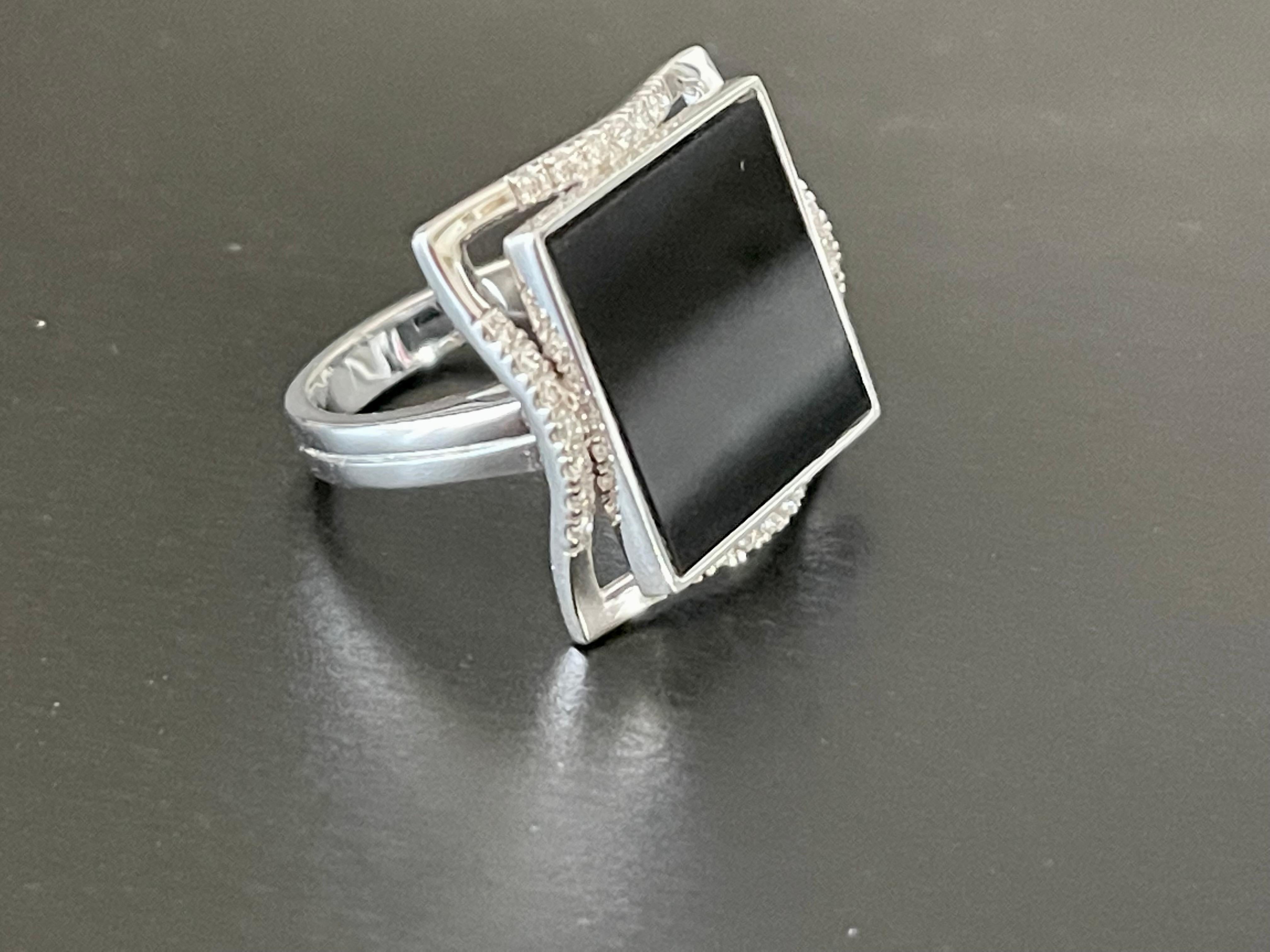 Attractive moder n 18 K whitel Gold Ring featuring 1 square cut Onyx that is accentuated by 28 brillant cut Diamonds weighing 0.20 ct. 
The ring is currently size 14/54( american ring size 7) but can easily be resized. 
Masterfully handcrafted