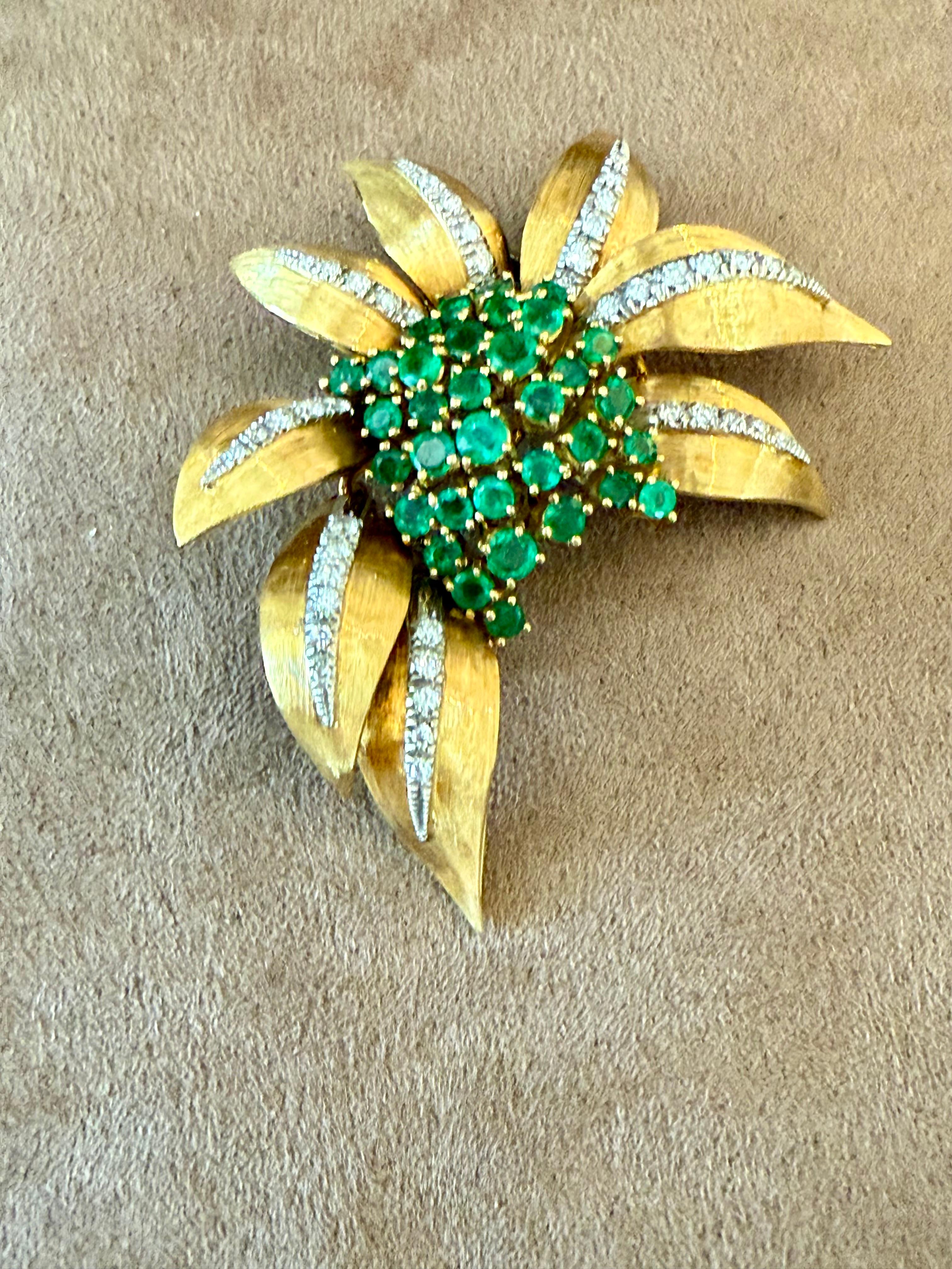This breathtaking vintage brooch pin is from circa the late 1960s. This Emerald and Diamond  brooch pin is hand-crafted in solid 18 K yellow and white Gold.
Featuring a gorgeous stylized flower with leaves, this elegant pin is covered with vivid and