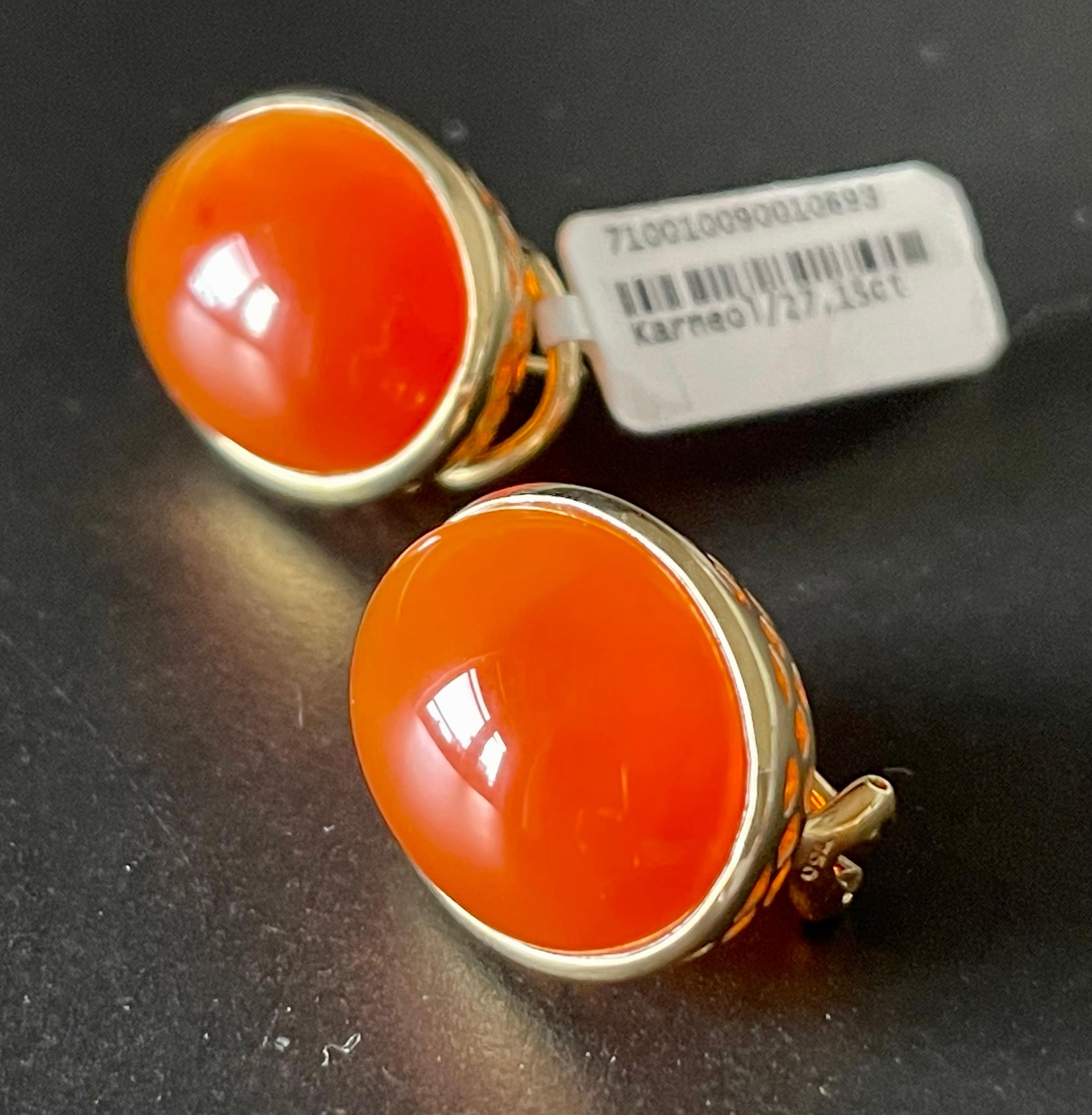 A pair of very understated yet simple 18 K yellow Gold earclips with Omega post featuring 2 orange Carnelian Cabochons in a bezel setting with a total weight of 27.15 ct. 
The earrings measure 1.72 cm width and 2.17 in length. 
Masterfully