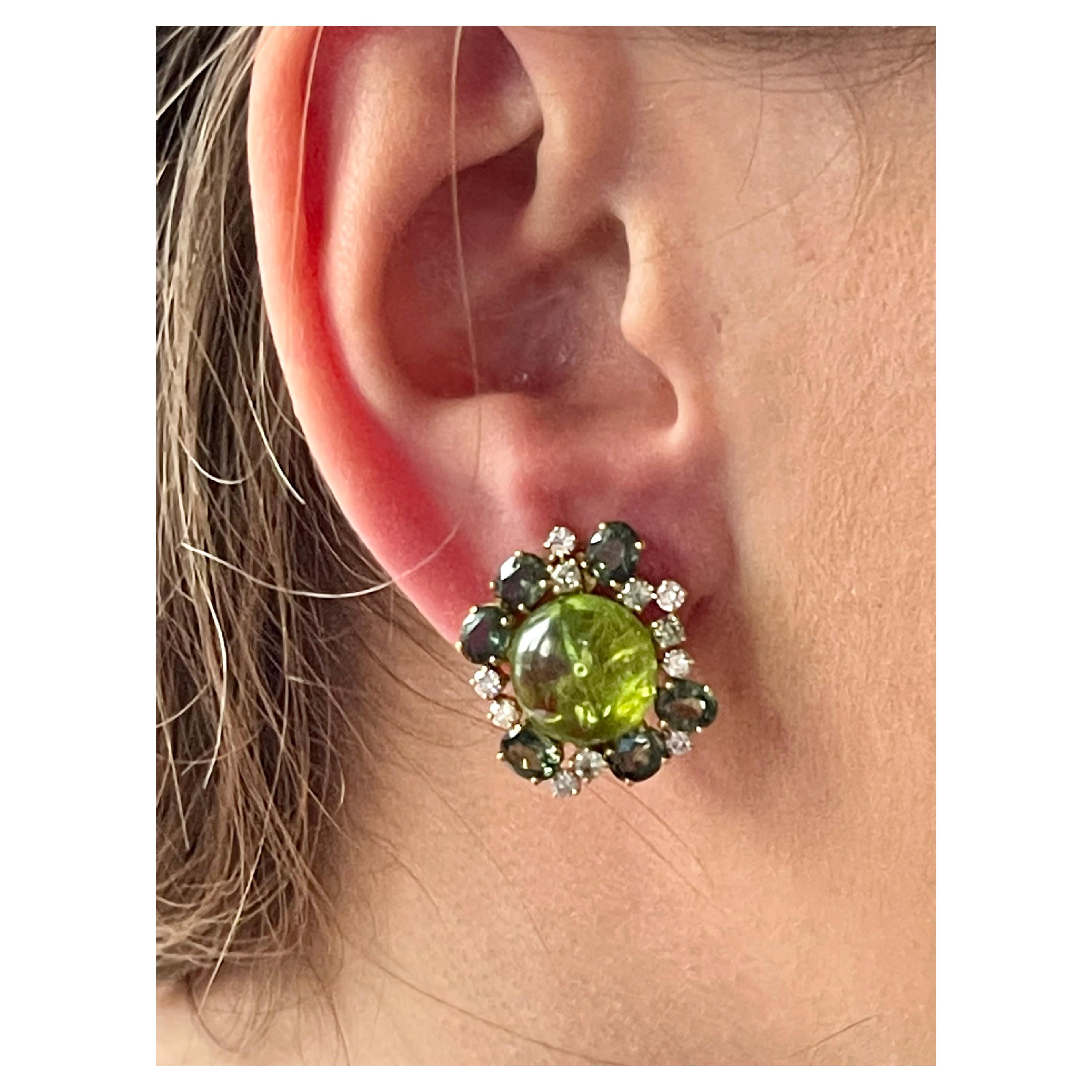 Exquisite clip-on cluster earrings crafted in 18 K yellow Gold feautring 2 Peridots Cabochons weighing 17.05 ct, 12 green Sapphires weighing 5.97 ct and Diamonds with a total weight of 
0.70 ct. The earclips can be worn on pierced ears and also on