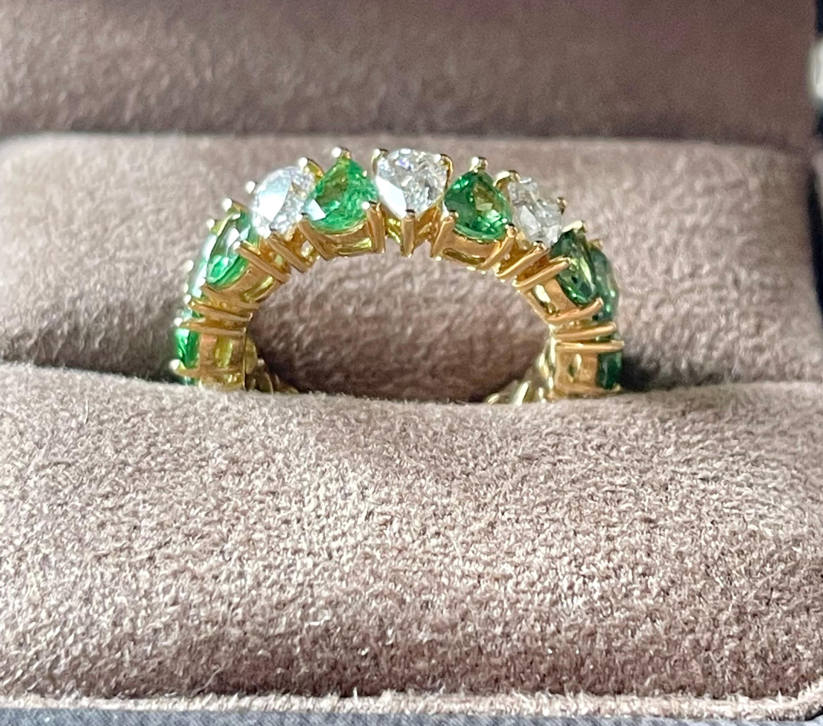An exquisite find. This 18 K yellow Gold prong set eternity ring features 14 vivid green pear shape Tsavorites with a total weight of 4.36 ct and 3 pear shape DIamonds weiging 0.89 ct, J color, I 1 clarity. Width of ring measures 6 mm at widest
