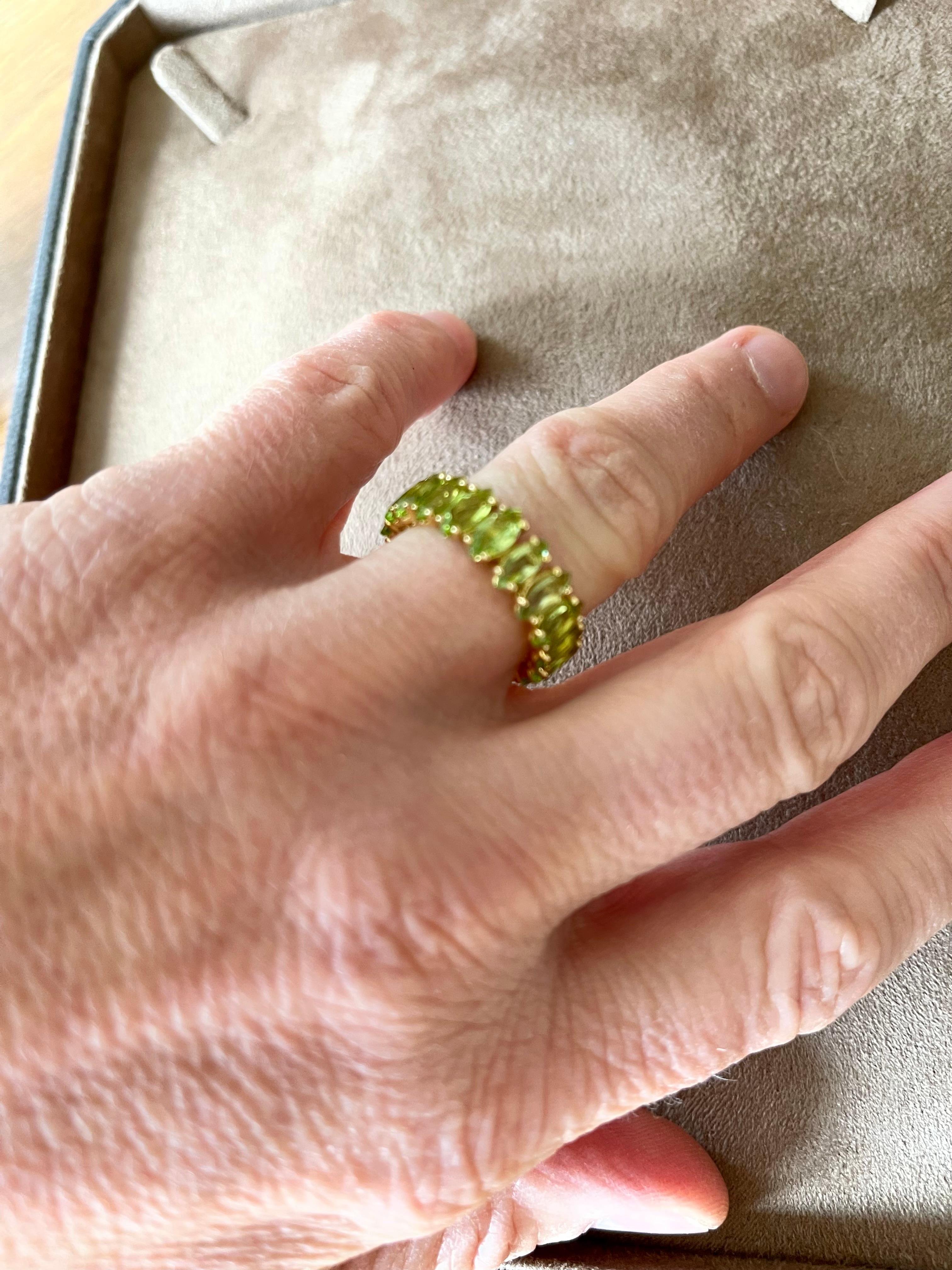 This 18 K yellow Gold eternity band features 19 marquise shaped Peridots weighing 7.01 ct. 
The ring size is currently a swiss 55/15,  American Ring size 7 1/2. The ring is stamped with makers mark and 750.
Masterfully handcrafted piece!