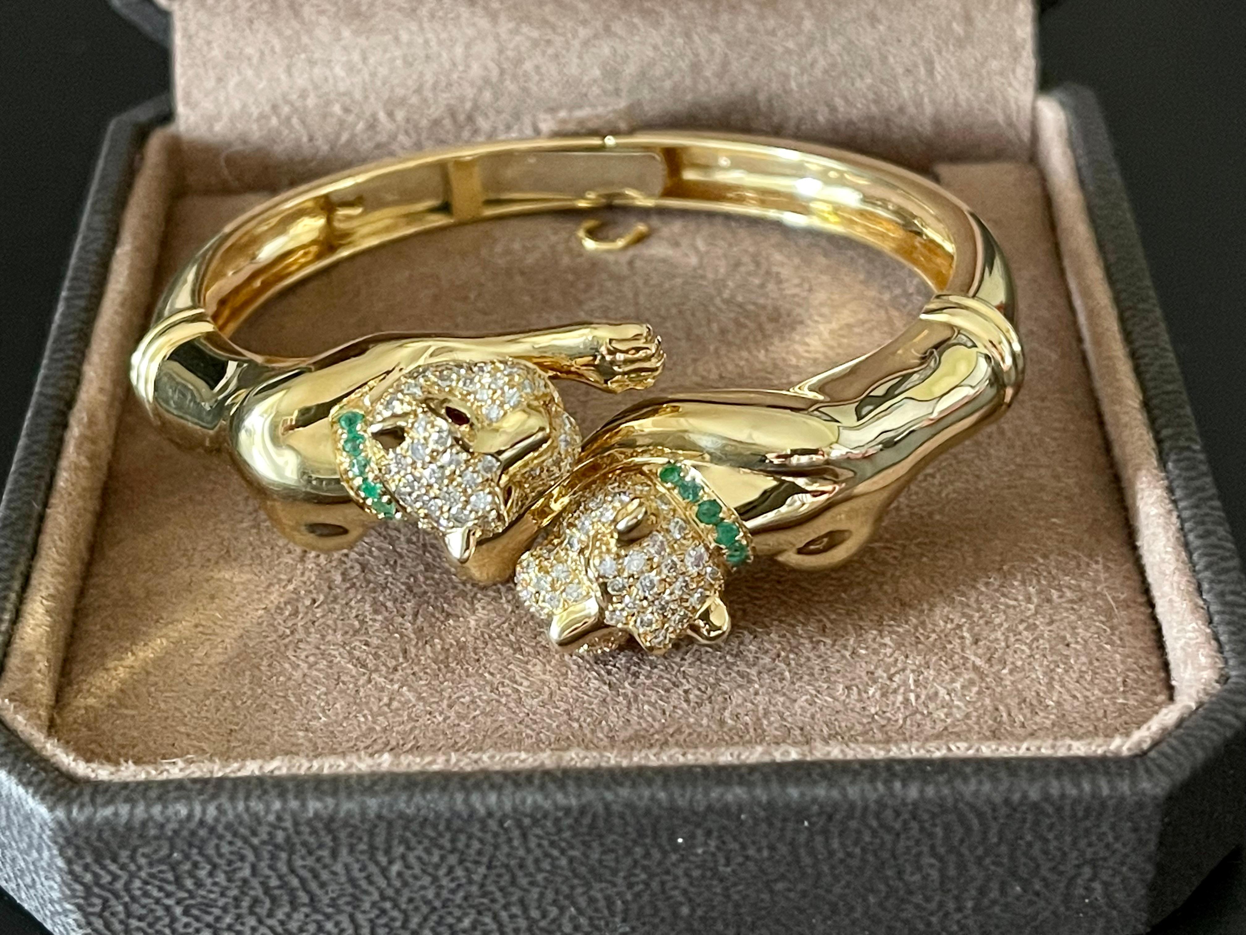 Captivating double Panther Head Bangle Bracelet finely crafted in 18 K yellowm Gold. Set with round brilliant cut Diamonds weighing approximately 1.20 ct, small Emeralds and Rubies. 
This stunning flexible bangle has an inner circumference of 16 cm