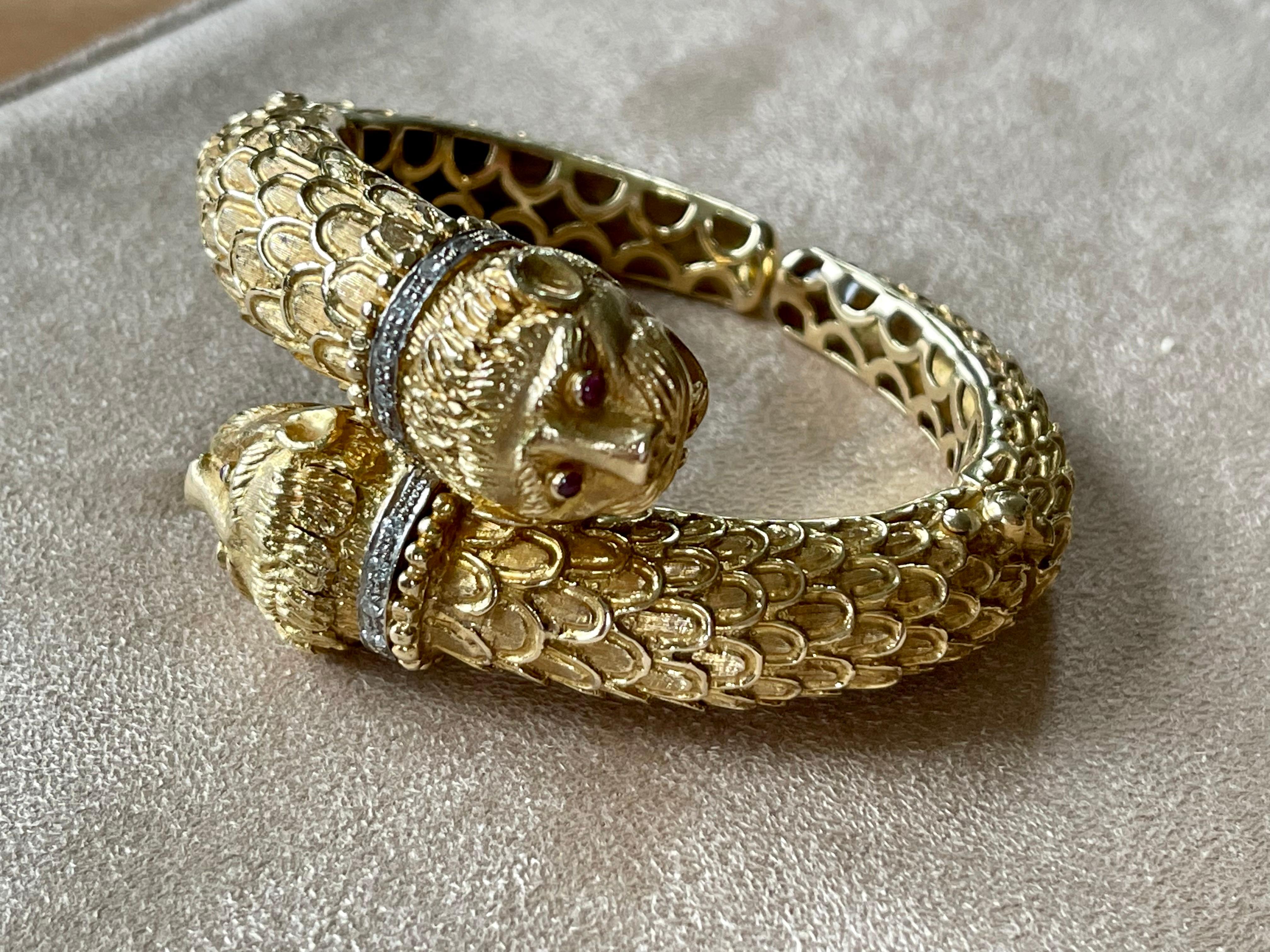 A very solid 18 K yellow Gold bangle bradelet of opposing Lion's heads.
The inner diameter is 5.5 cm that will suit small to medium wrists. The gazing eyes of the 2 lions are created with 4 natural pink Tourmalines. The lions are set with tiny