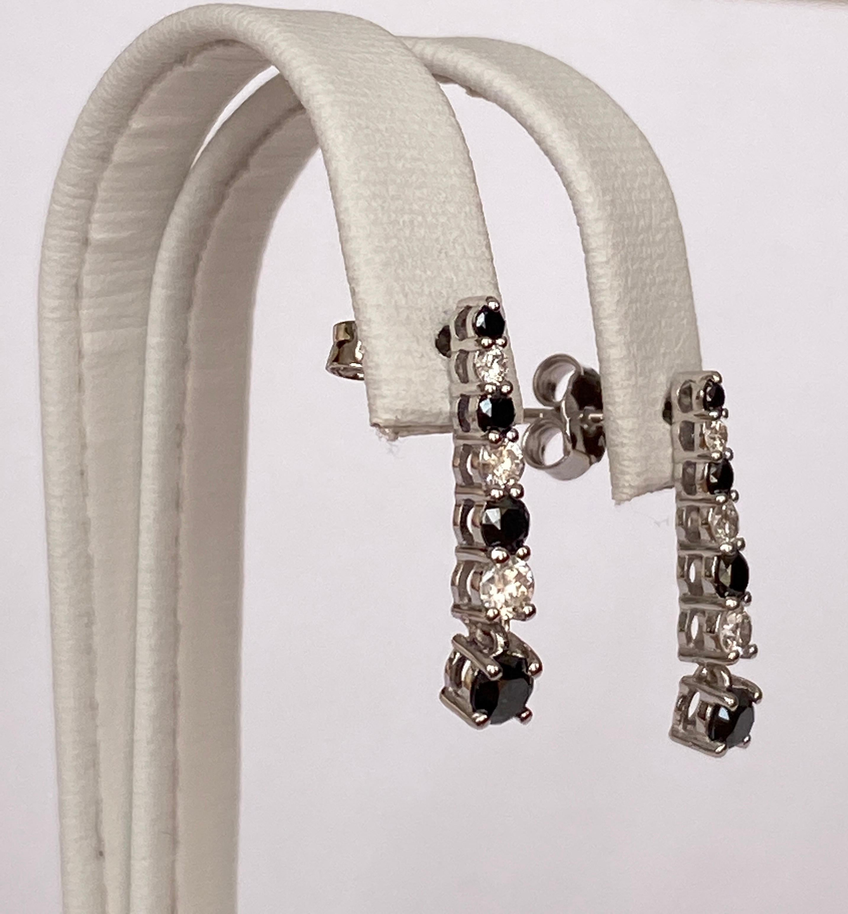 Offered in new condition: white gold dangle ear studs decorated with 6 pieces of  brilliant cut diamonds, in total approx.0,30 ct H/VS/SI , and 8 pieces of Black  diamonds of approx. 0,50 ct. In total approx. 0,80 ct in diamonds.
Length:1,9 cm
Gold