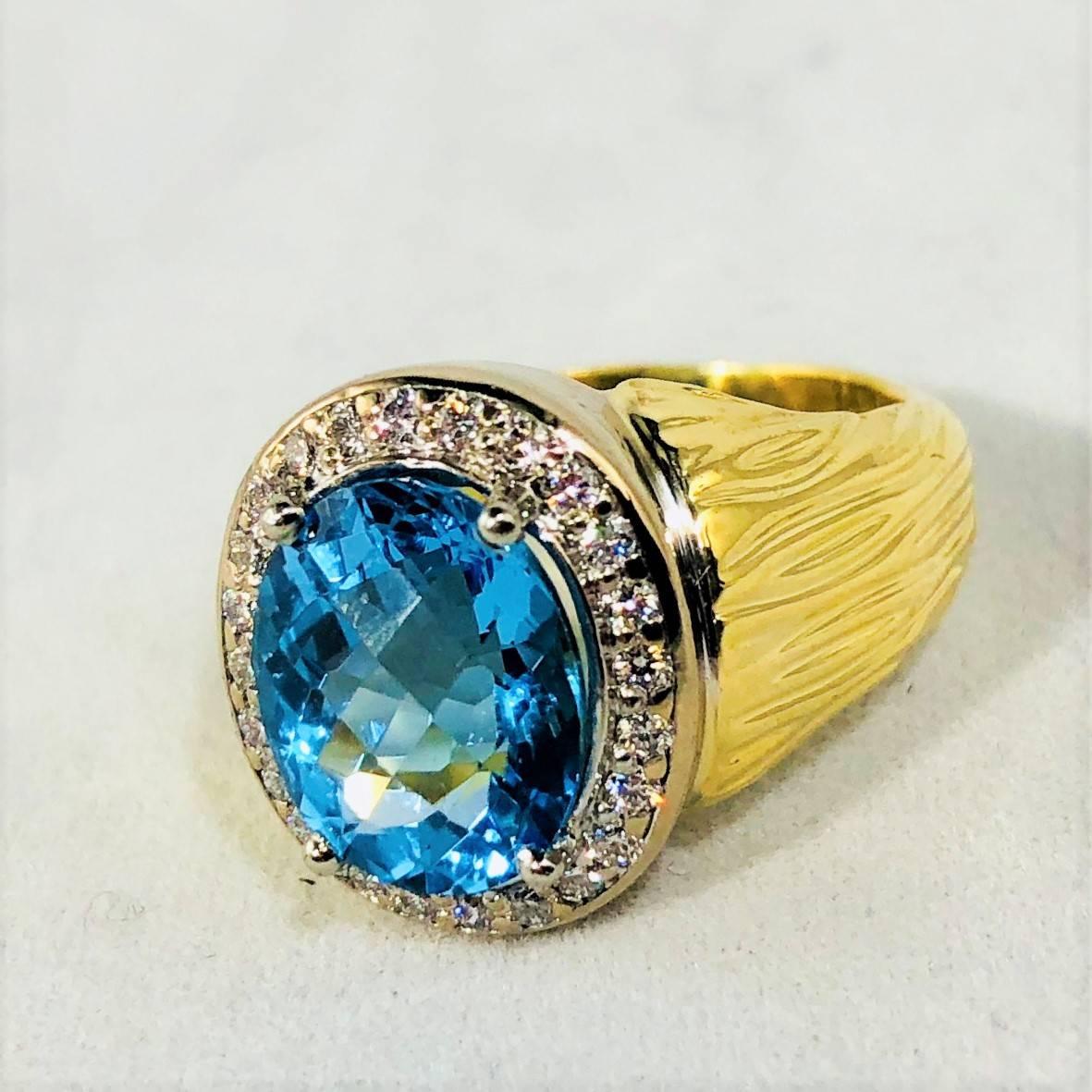 18 karat yellow gold and white gold blue topaz and diamond ring, 1- oval blue topaz measuring 11mm x 9mm, bright light blue color, 24- full cut round diamonds = .23 carat total weight, average color G-H, average clarity VS1, 18 karat  weight 11