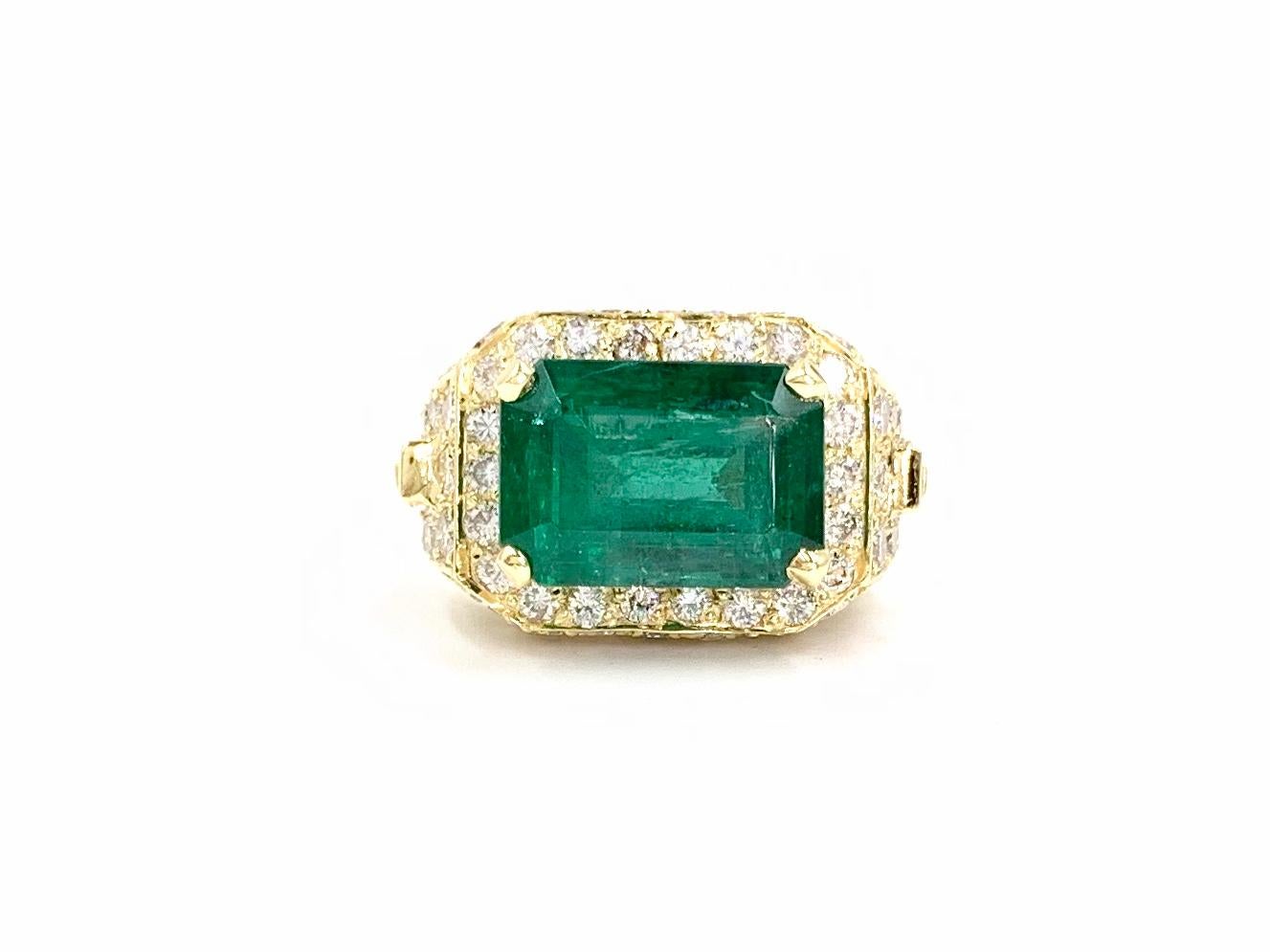 An 18 karat yellow gold 5.87 carat green Emerald cocktail ring has a modern design with a touch of Art Deco influence. The emerald cut genuine green emerald is vivid and well saturated, set horizontally for a unique look. Emerald is surrounded by