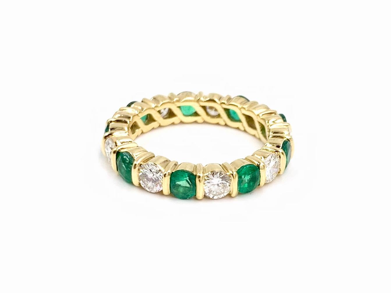 Round brilliant diamonds and green emeralds are beautifully bar set in 18 karat yellow gold in a classic alternating designed band ring. 9 high quality diamonds have a total weight of 1.54 carats at approximately F-G color, VS2 clarity. 9 vivid
