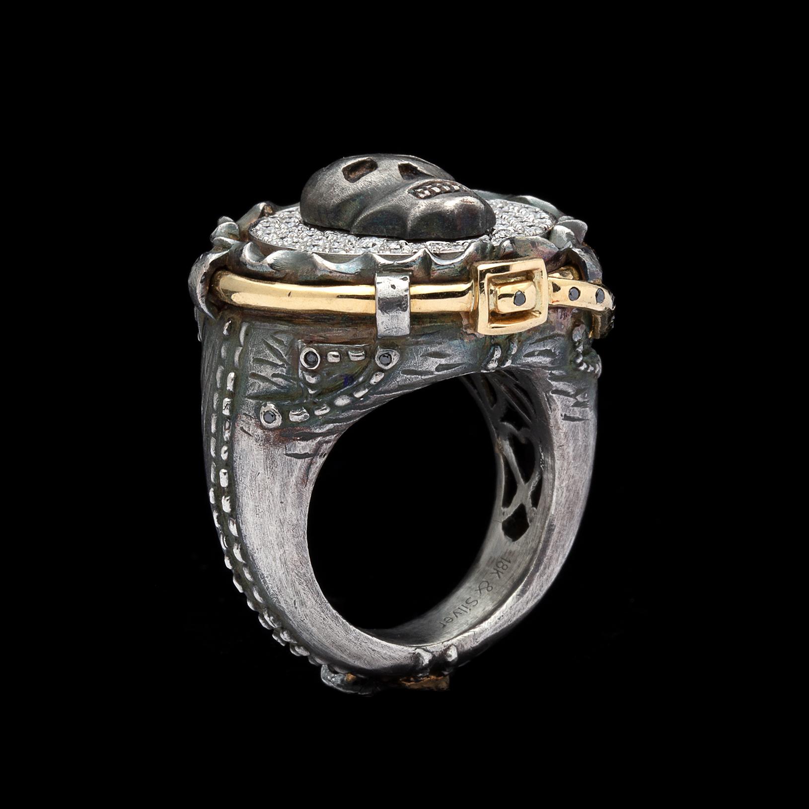 Be outrageous with this fun silver and 18k gold ring! Featuring a skull amidst a bed of round brilliant-cut diamonds, set atop a pair of blackened silver jeans compete with a black diamond-set gold belt. Estimated diamond weight is 0.70 carat. The