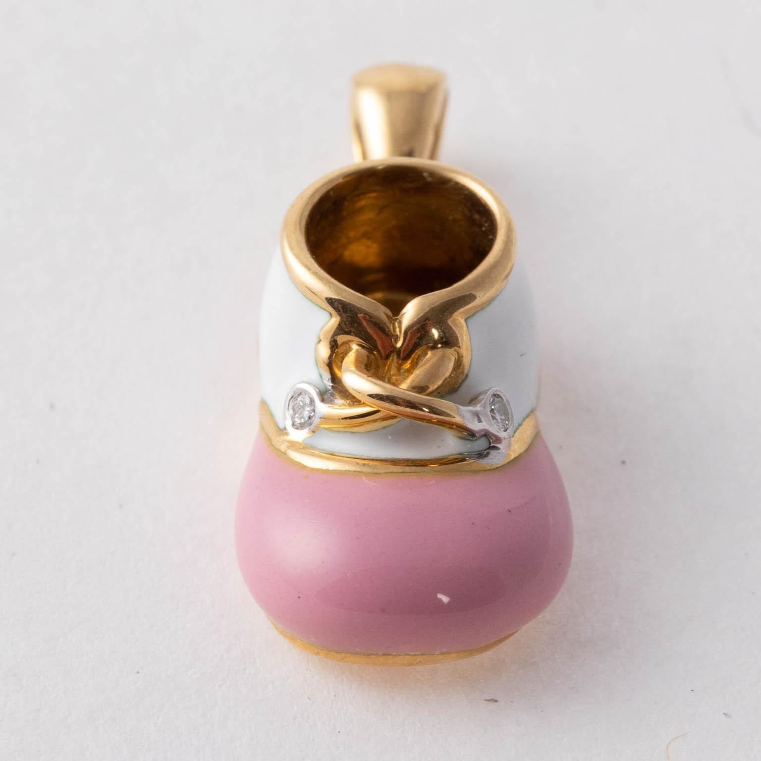 Circa late 20th century baby shoe by Felix Vollman detailed in pink and white enamel accented with an 18 karat Gold lace and two diamonds. The piece can be worn for either a necklace pendant or charm bracelet. Please note of wear consistent with