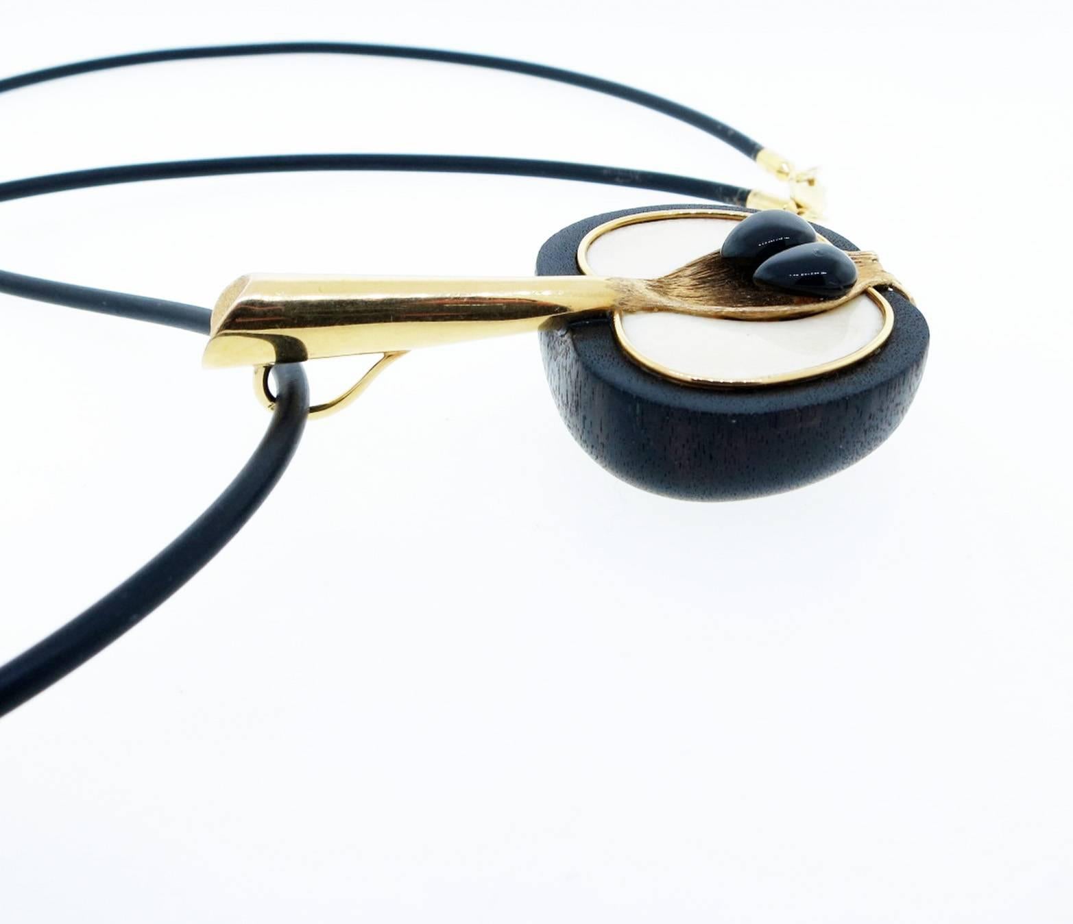 18kt. yellow gold dimensional apple pendant made of fruit wood with a bone inlay with onyx seed accents . The pendant measures 3 3/4 inches in length . The rubber cord measures 30 inches in length