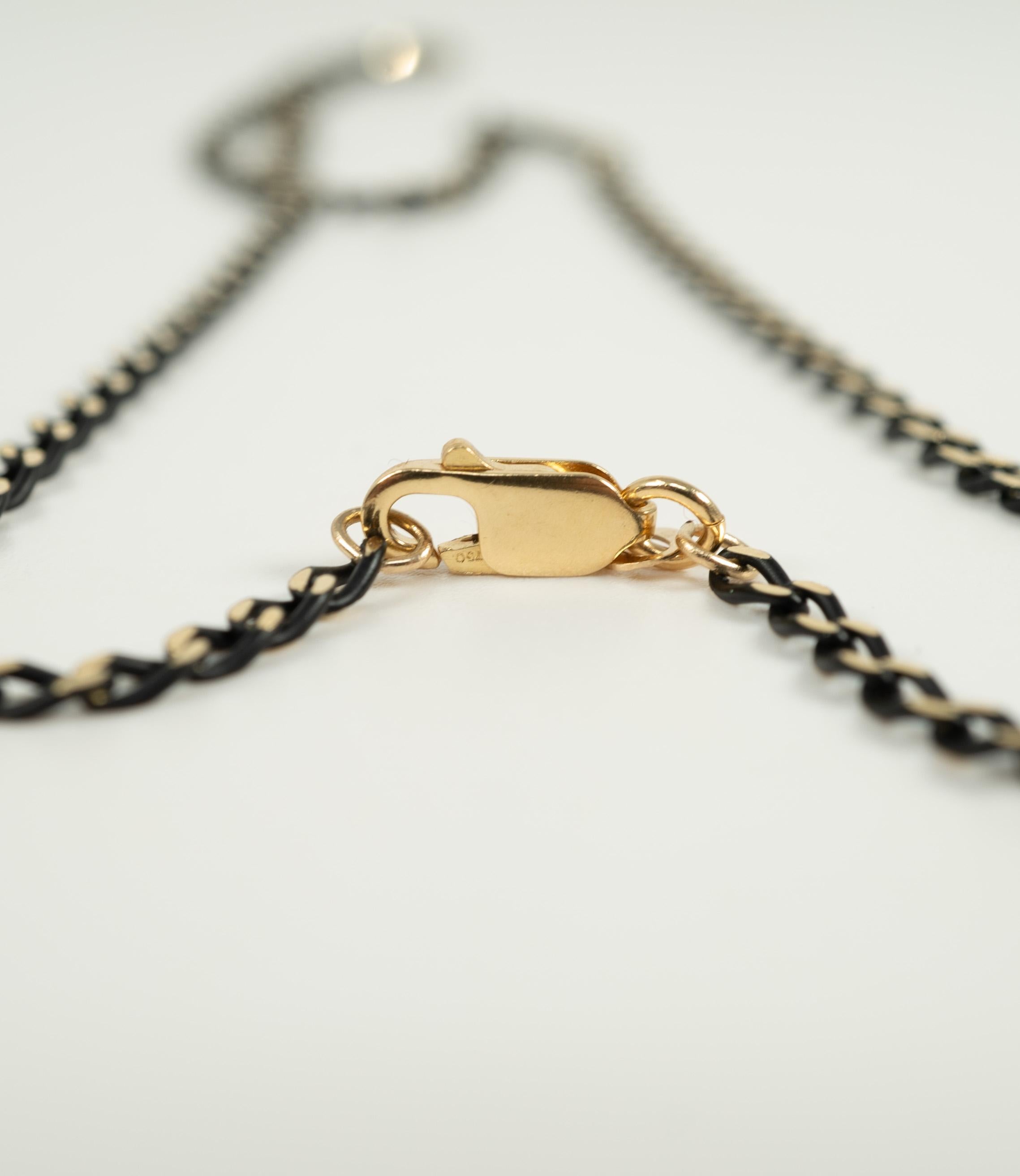 In 18 karat black and yellow gold, secured with a lobster clasp.