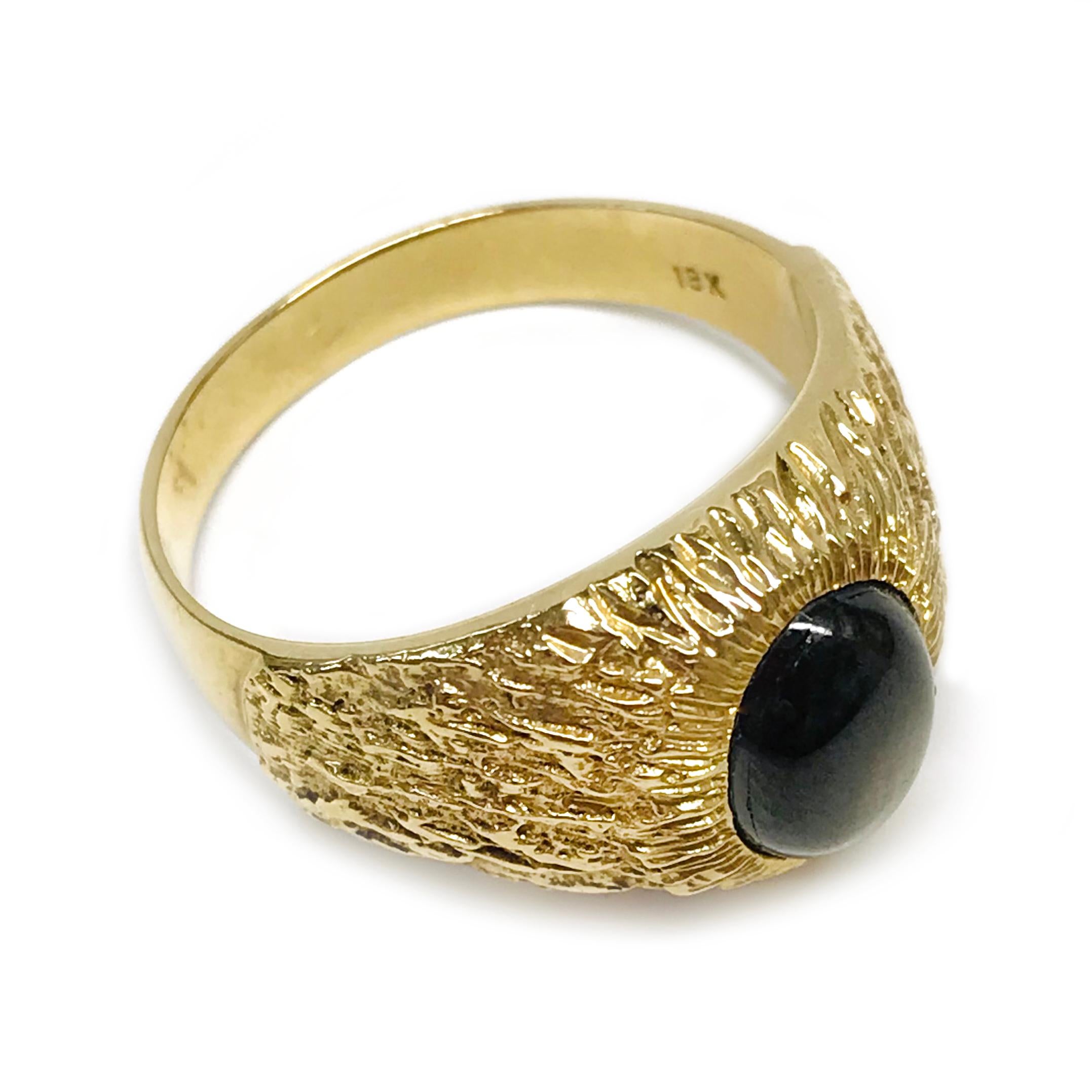 18 Karat Black Star Sapphire Ring. The ring features a bezel-set oval black star sapphire. The six-star sapphire is has good presence with light. The sapphire measures 9mm x 7mm and the ring size is 9 1/2. Approximately half of the ring band has a