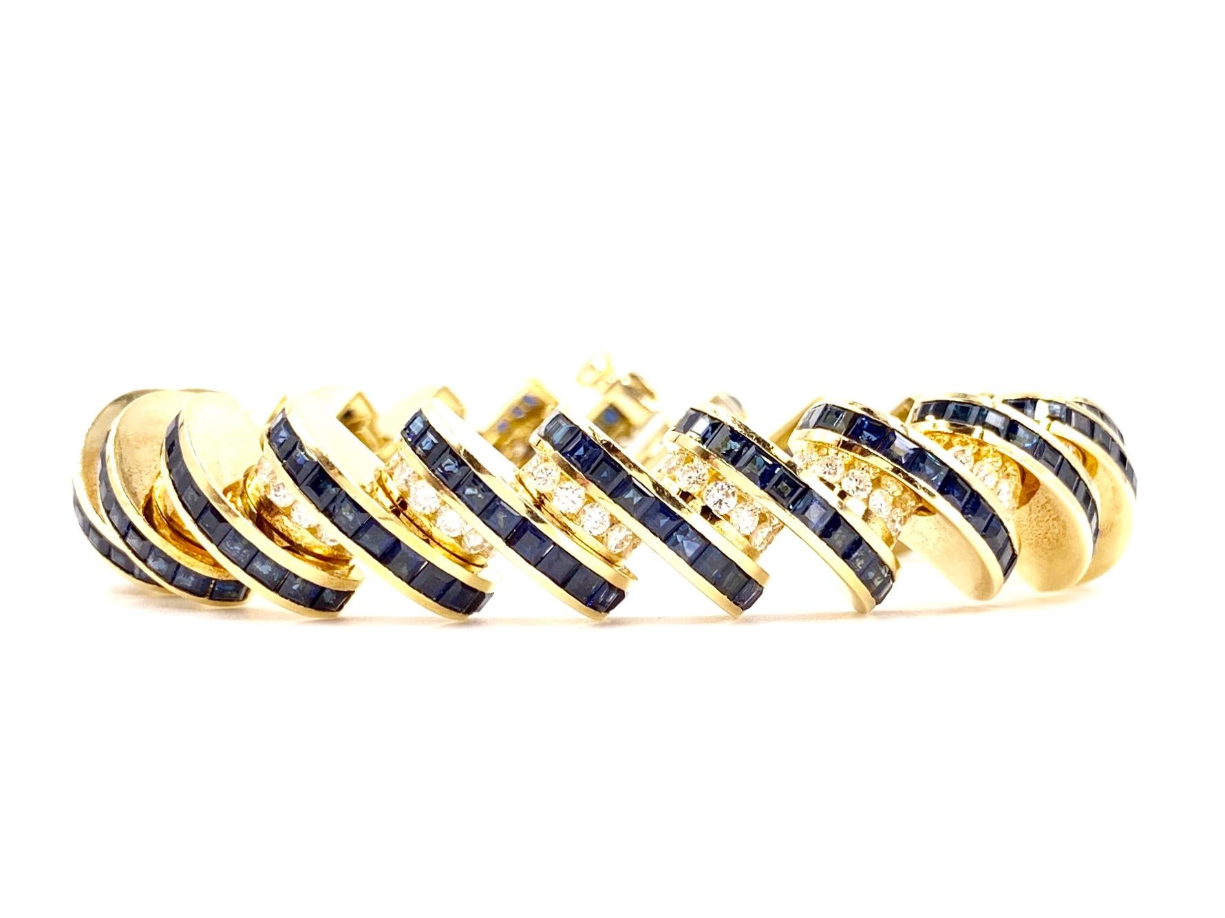 Finely crafted by Charles Krypell. This heavy and substantial 18 karat yellow gold modern style bracelet features 242 calibrated blue sapphires at approximately 12.10 carats total weight and 132 bright white round brilliant diamonds at approximately