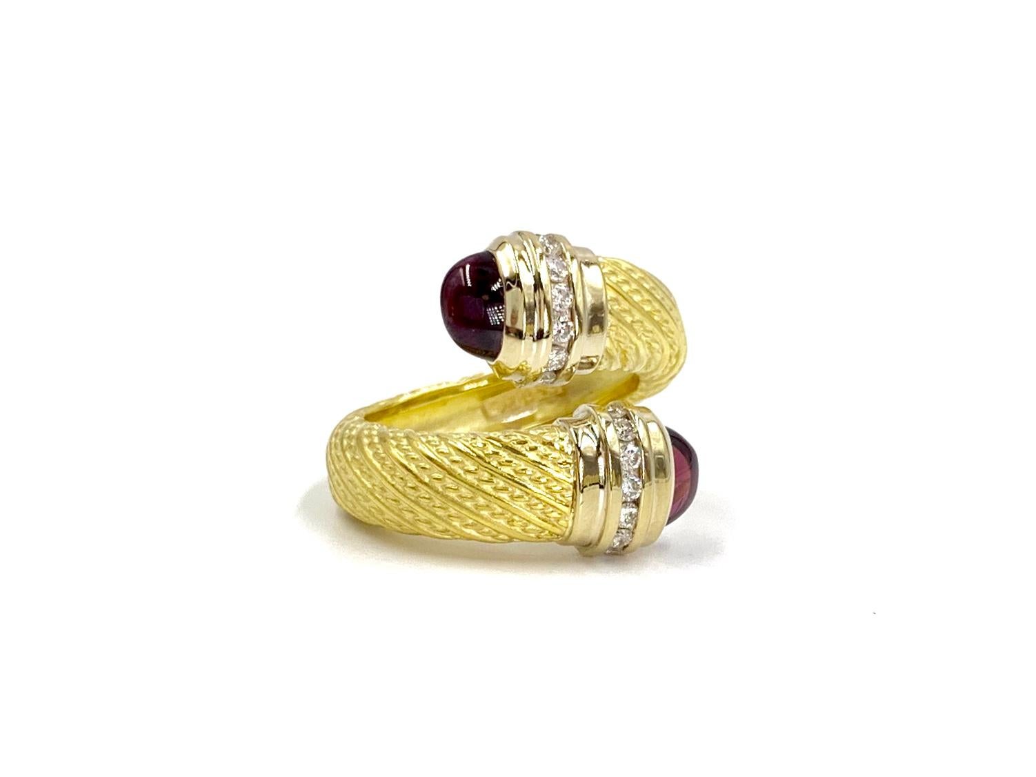 Made with extraordinary craftsmanship by Seidengang jewelry company. This 18 karat hand carved bypass wrap style ring features two cabochon rhodolite garnet caps and .20 carats of round brilliant diamonds. Diamond quality is approximately G color,