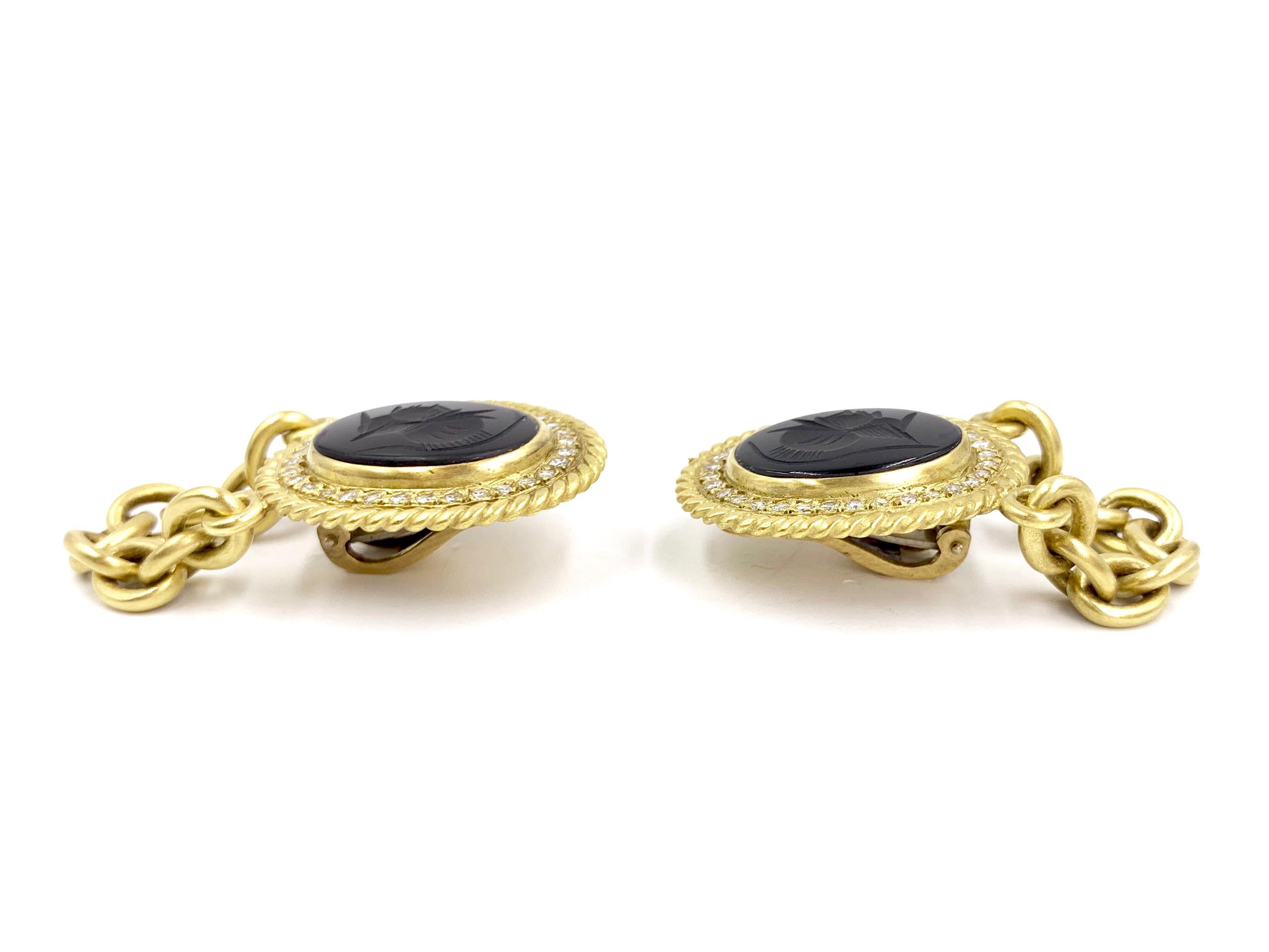Fashionable brushed 18 karat yellow gold chain drop earrings featuring onyx with intaglio soldier profile surrounded by white diamonds. Earrings have a diamond total weight of .96 carats at approximately F-G color, VS2 clarity. 
Earrings are fixed
