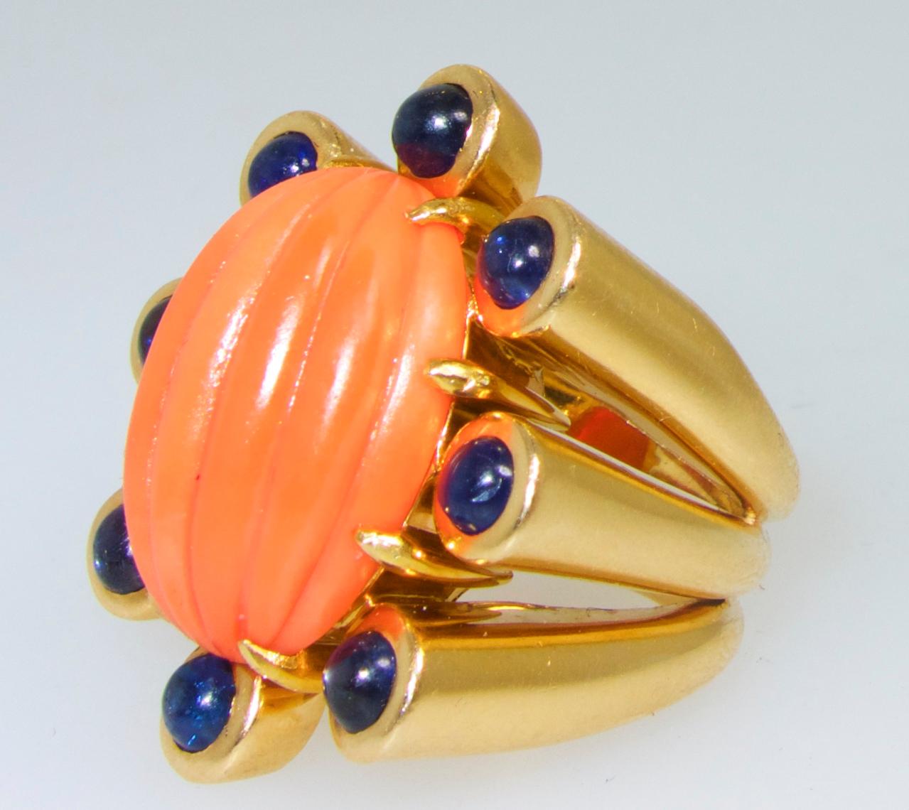 Melon - cut natural orange coral surrounded by 8 natural deep blue natural (unheated and untreated), sapphires weighing totally 2.0 cts.  This bold and impressive ring is a size 7 and an iconic late retro-'60's design.  This ring can be sized.