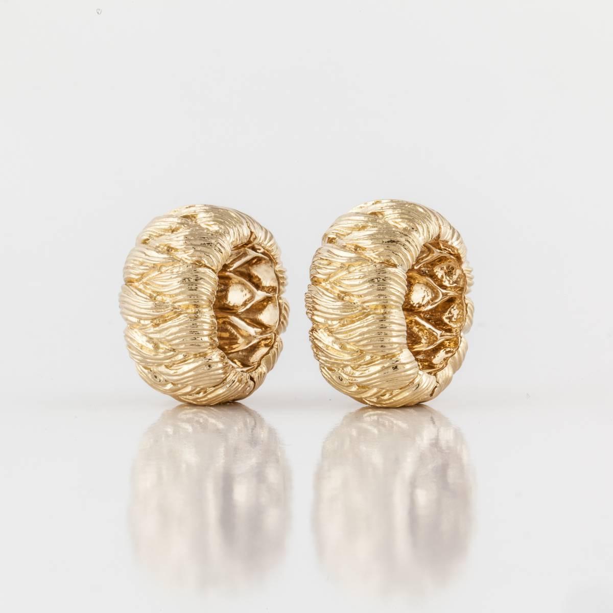 David Webb textured hoop earrings crafted in 18K yellow gold.  The gold is deeply textured with a classic design.  They measure 1 inch long and 3/4 inches wide.  Clip style.