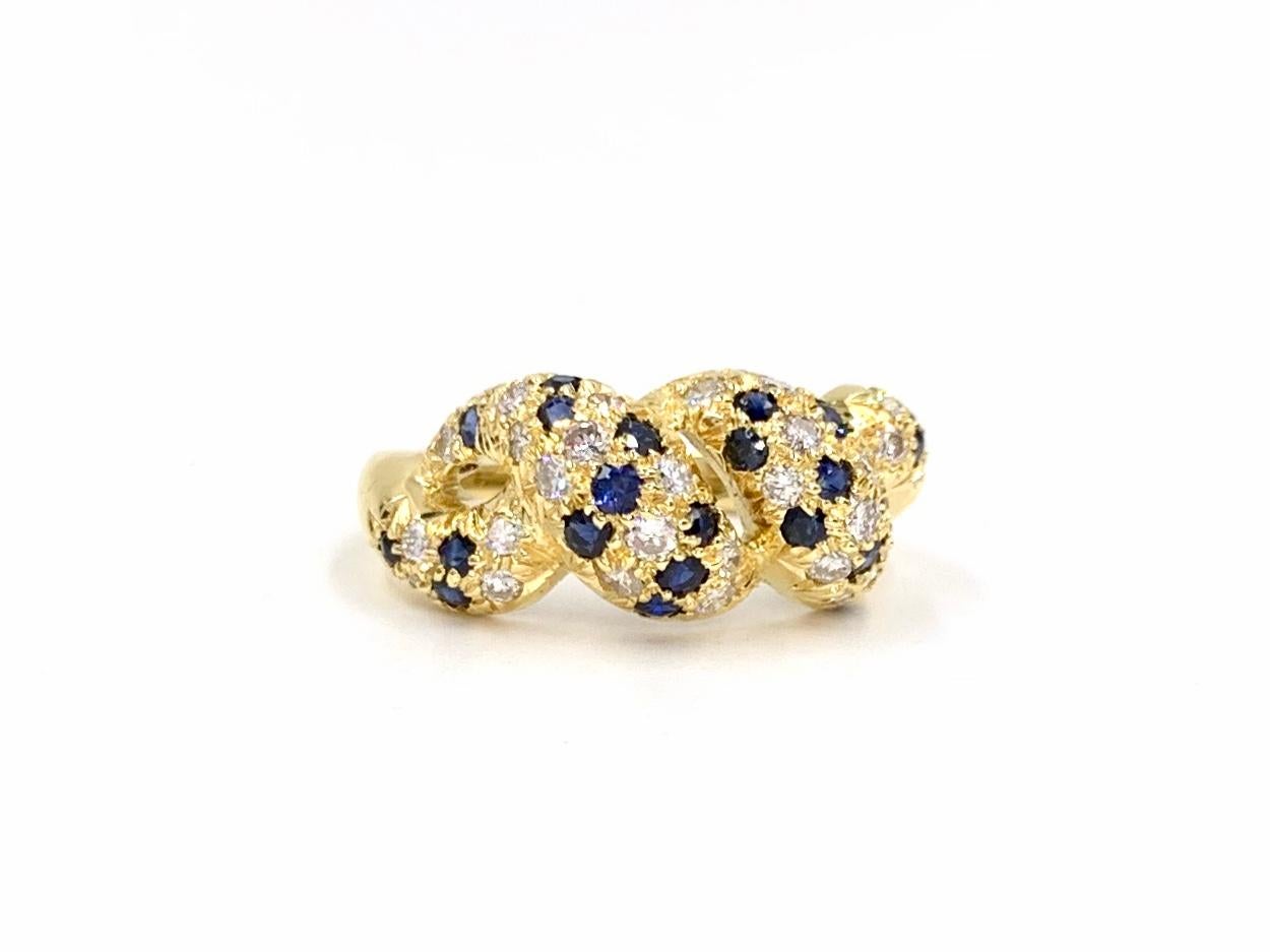 A wearable 18 karat yellow gold open twist ring featuring pave set white diamonds and blue sapphires. 38 round brilliant diamonds have a total weight of .85 carats at approximately G color, VS2 clarity. Blue sapphires are well saturated. Width of