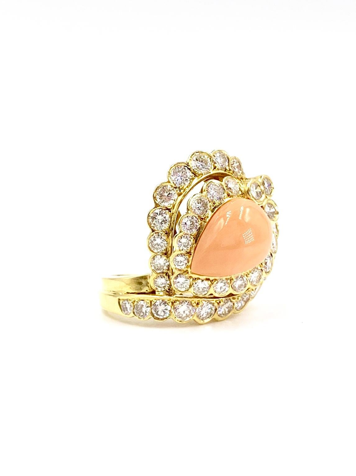 Elegant and sophisticated yet stylish, this well crafted unique 18 karat yellow gold cocktail ring features a well saturated light peachy-pink pear shape coral surrounded by beautifully bezel set round brilliant diamonds. 37 Round brilliant diamonds