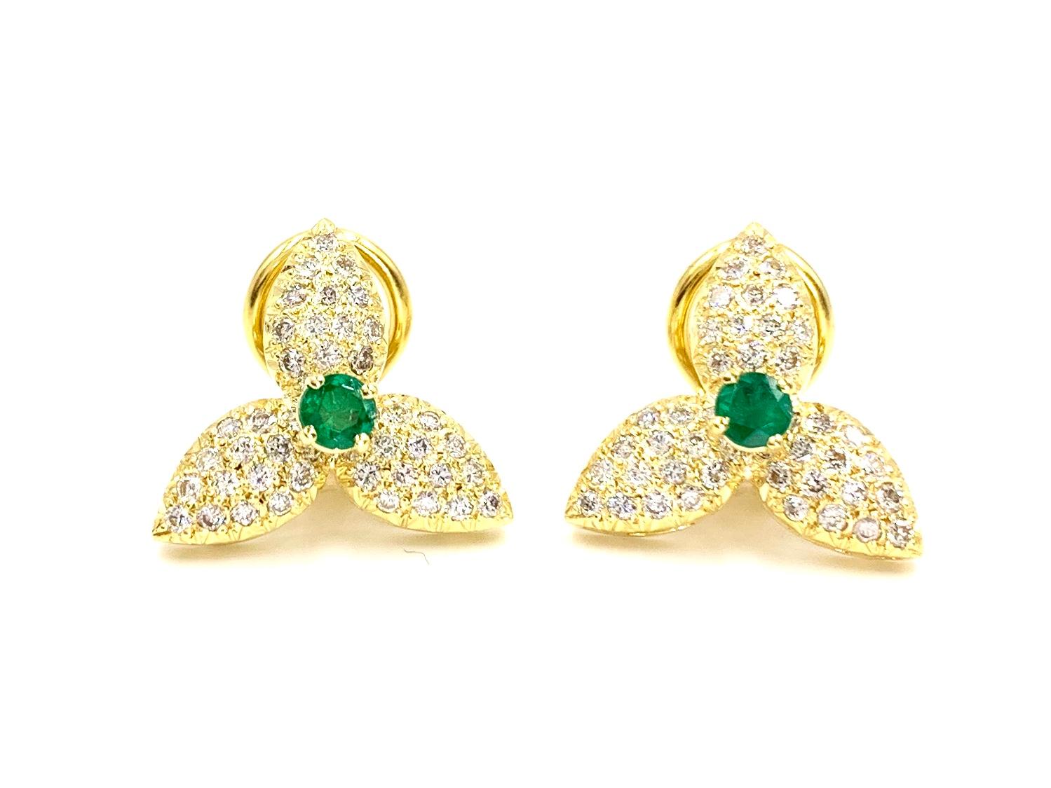 Beautiful and wearable 18 karat yellow gold clip-on stud style floral earrings featuring pave set round diamonds on the petals and a vivid green emerald center. Earrings have a total diamond weight of 1.14 at approximately F color, VS2 clarity. Two