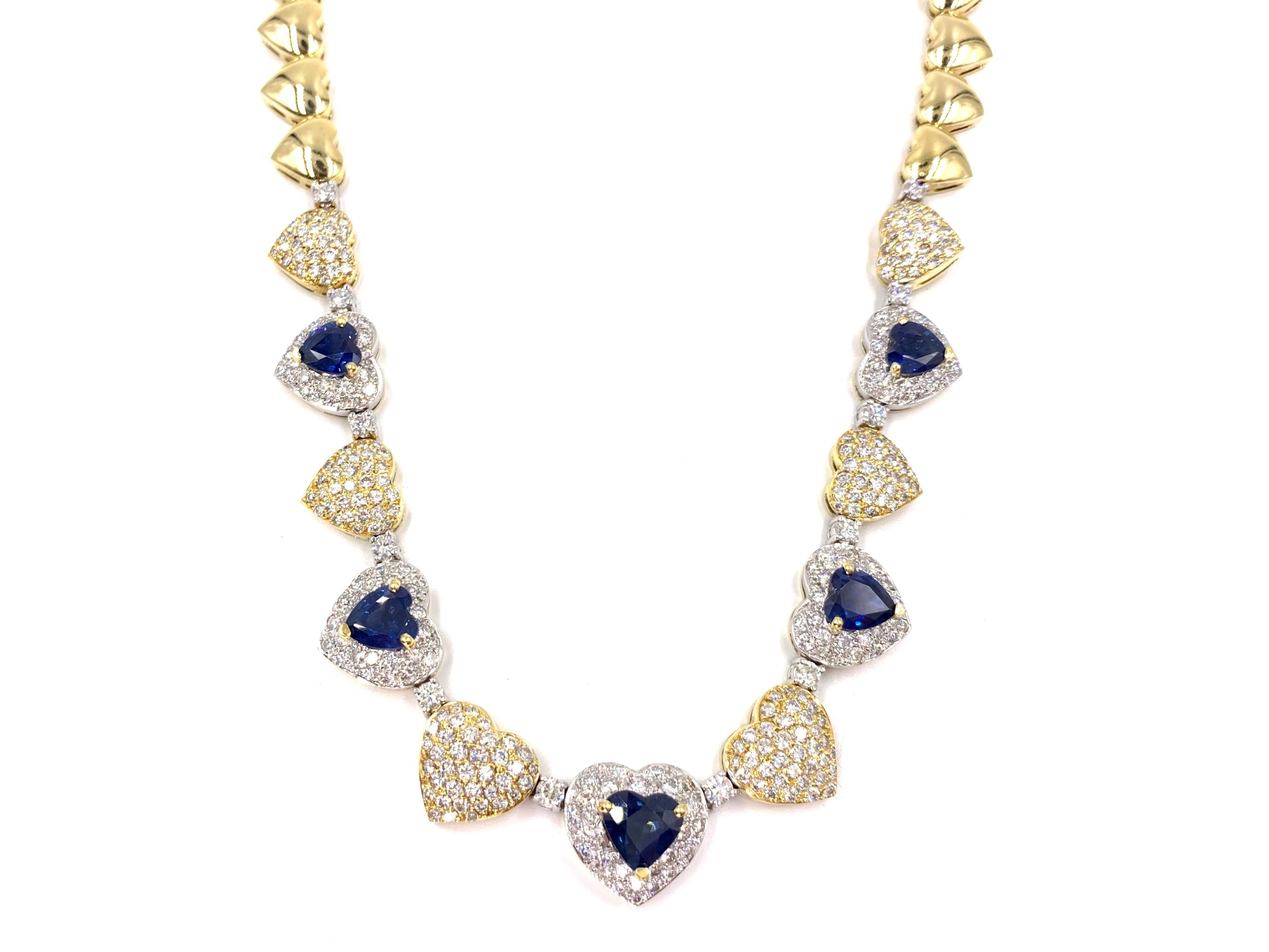 An absolute stunner, crafted with quality. This 18 karat white and yellow gold graduated heart necklace features five heart shaped blue sapphires at 7.90 carats total weight and 7.65 carats of high quality white round brilliant diamonds. Blue