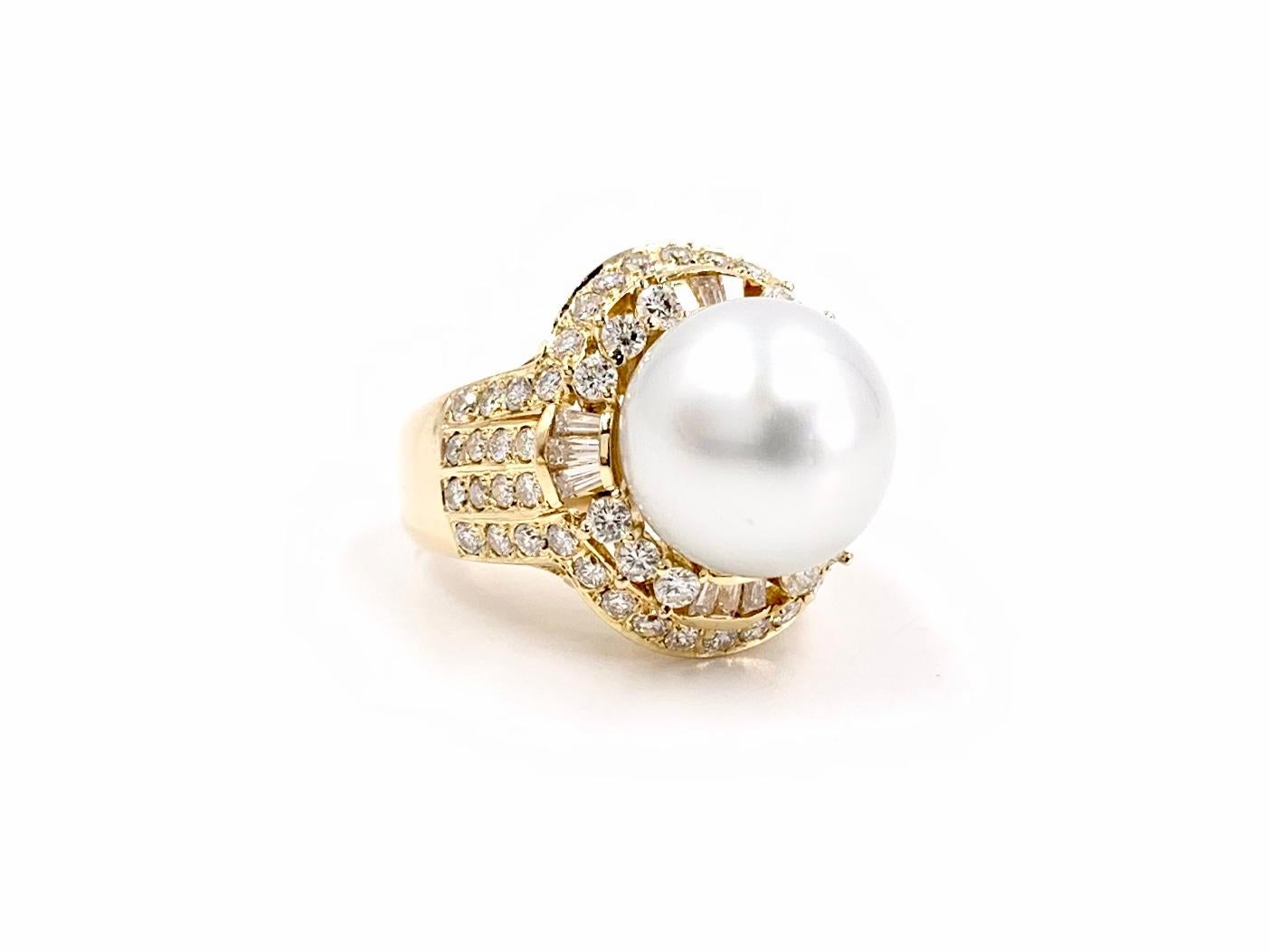 A beautiful and substantial polished 18 karat yellow gold genuine South Sea pearl and diamond cocktail ring. Ring features a 12mm lustrous white South Sea pearl center surrounded by round brilliant and baguette diamonds, arranged in an elegant and