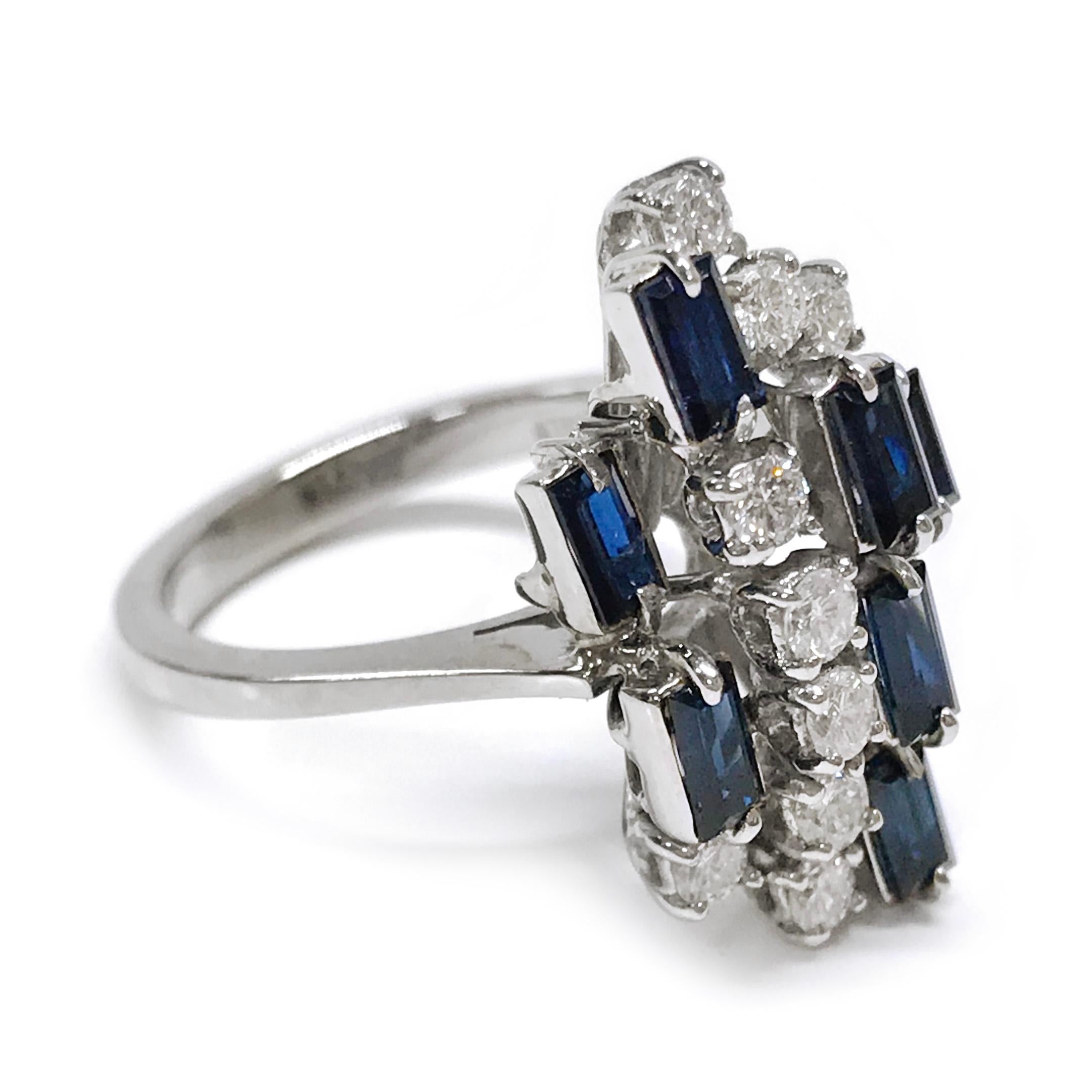 Anello con diamante 18 carati e zaffiro blu con taglio smeraldo. L'anello a grappolo presenta nove diamanti rotondi e otto zaffiri blu taglio smeraldo incastonati in livelli di diverse altezze. Gli zaffiri sono incastonati e i diamanti sono