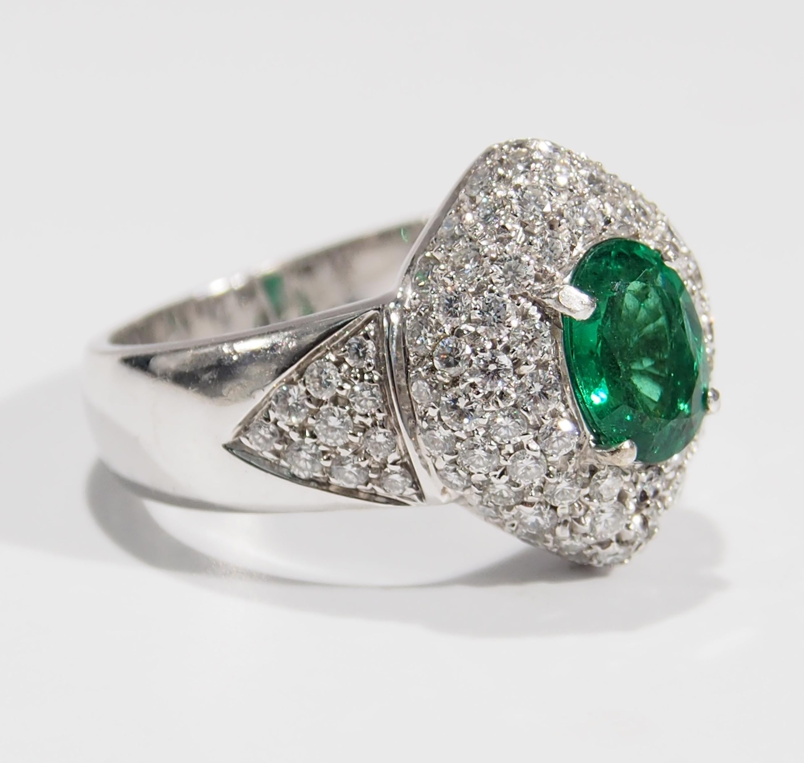 This is a sparkling 18K White Gold Diamond and Emerald Cluster Ring with approximately (94) Round Brilliant Cut Diamonds, 1.18ctw, G-H in Color, VS in Clarity that surround an exquisite Oval Emerald, 1.00ct. A stunning Ring to wear for any occasion