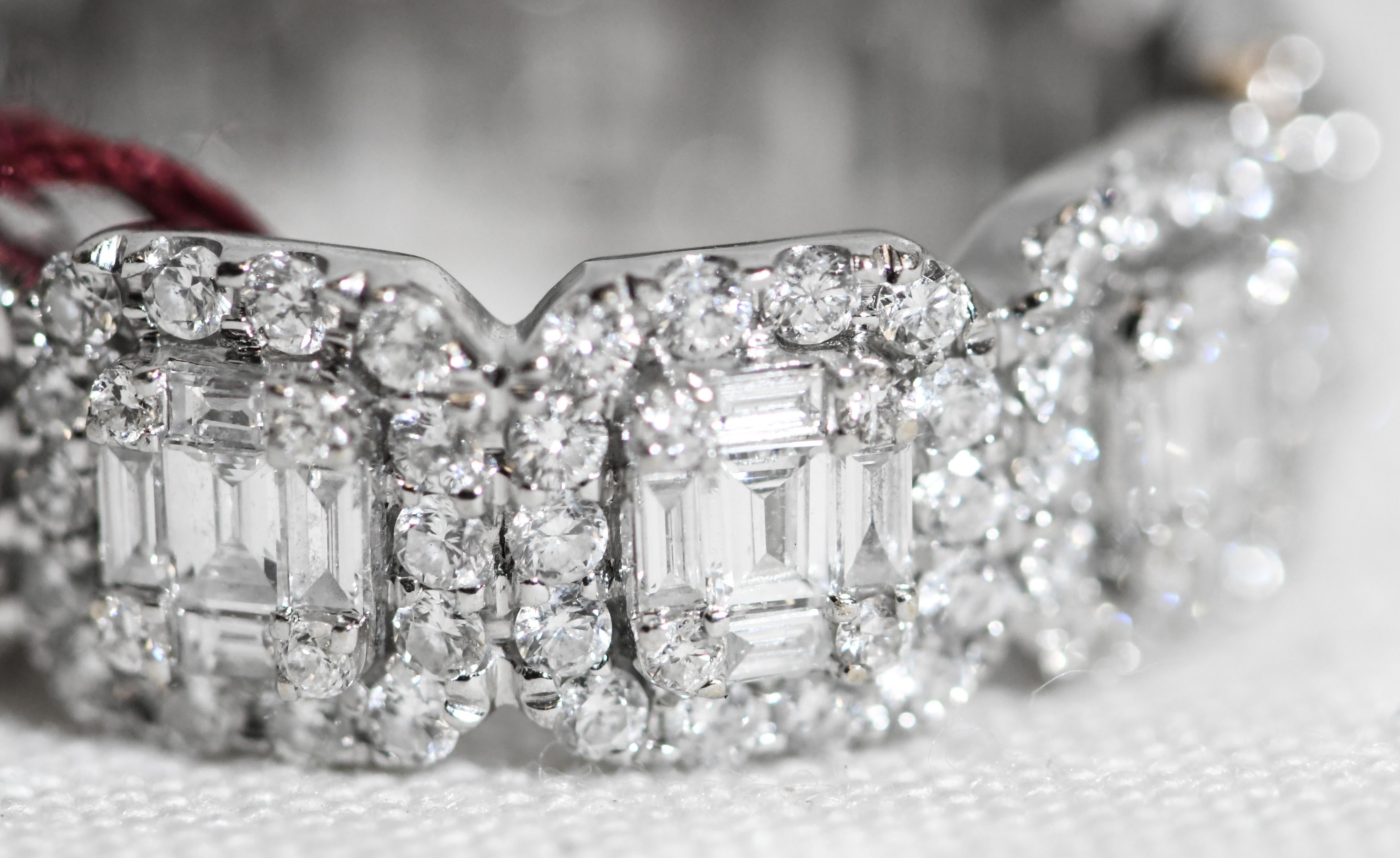 Meticulously crafted in 18 karat white gold, this stunning Eternity Band is genius of design.  Each section appears to contain an emerald cut diamond in the center.  Closer inspection reveals each station containing at the center baguette diamonds