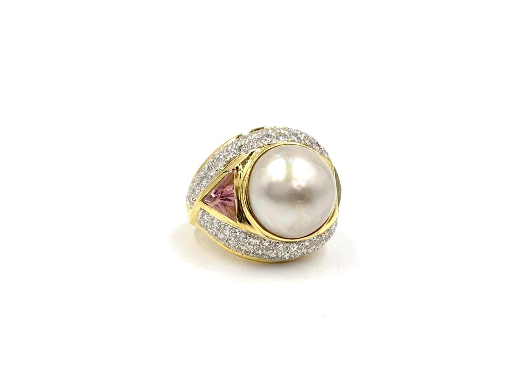 A unique 18 karat yellow gold large cocktail ring featuring 2.40 carats of round brilliant white diamonds, a 14mm lustrous mabe pearl, trillion topaz in both blue and pink. Diamond quality is approximately F-G color, VS2 clarity and perfectly pave