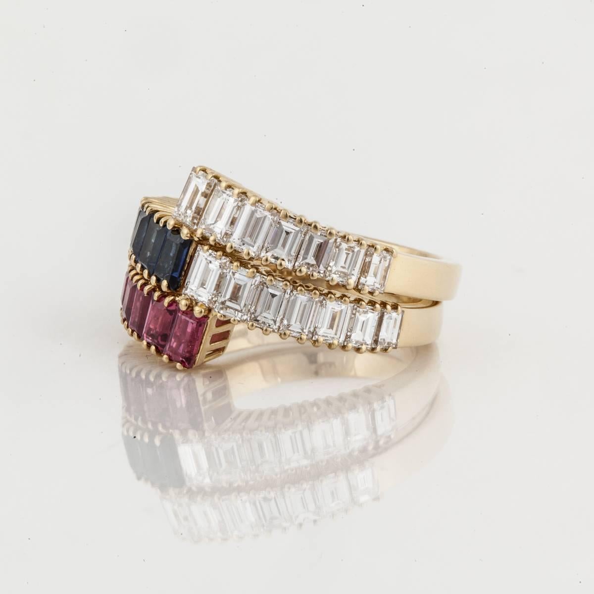 Two crossover style bands composed of 18K yellow gold.  One band has baguette rubies and baguette diamonds.  The other band has baguette sapphires and baguette diamonds.  They can be fitted to stack/nest together or can be worn individually.  Each