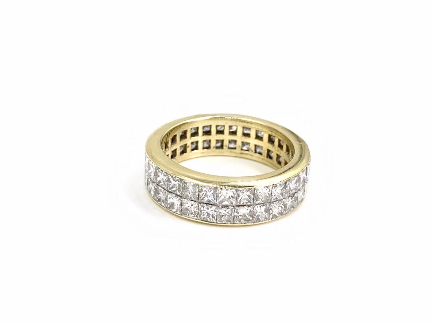 A timeless eternity band with sleek design and a generous amount of sparkle. This 18 karat yellow gold  6.5mm band features two rows of invisibly set princess cut diamonds at approximately 5 carats total weight. Diamond quality is approximately F-G