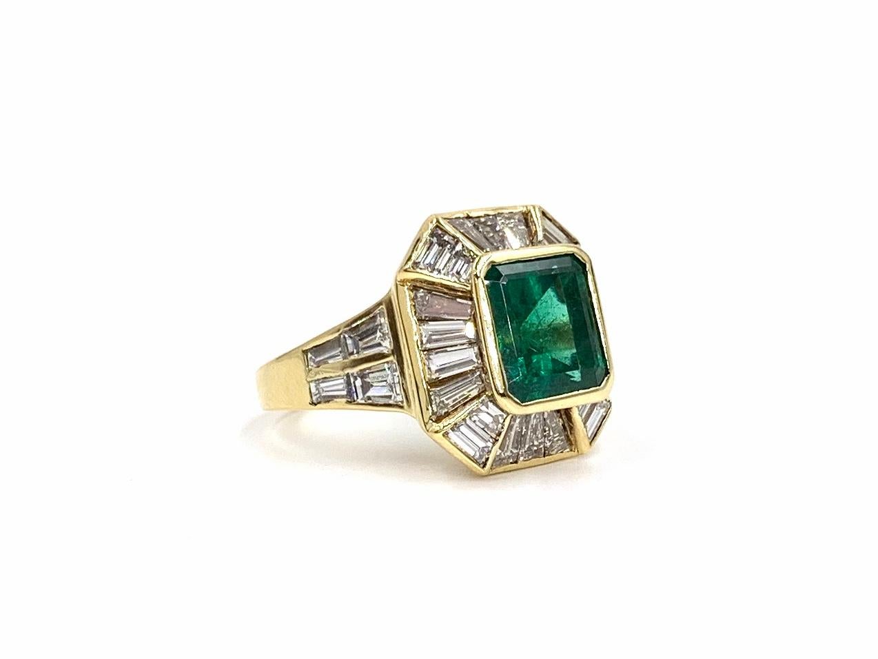 A beautiful, well made 18 karat yellow gold ring featuring a genuine saturated emerald at approximately 2.50 carats surrounded by approximately 3 carats of baguette cut white diamonds. Diamonds are approximately F-G color, VS2 clarity (eye clean).