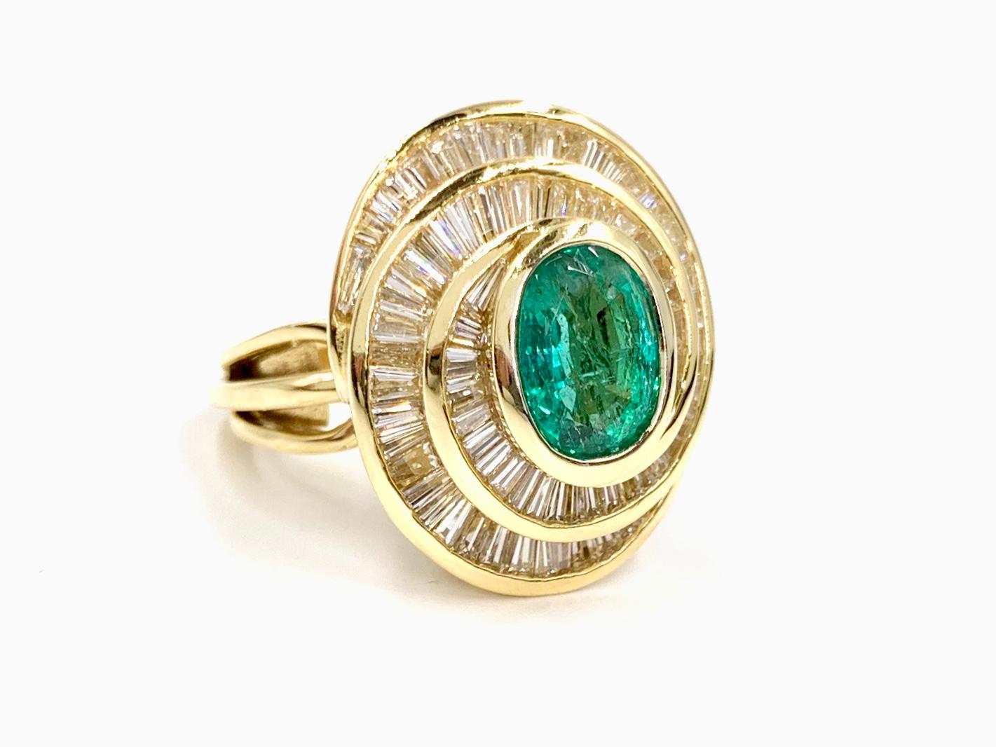 An extraordinary find. This 18 karat yellow gold large cocktail ring features a unique swirl design with expertly cut and set channel set baguette diamonds showcasing a substantial oval vivid emerald center. Oval emerald weighs approximately 2