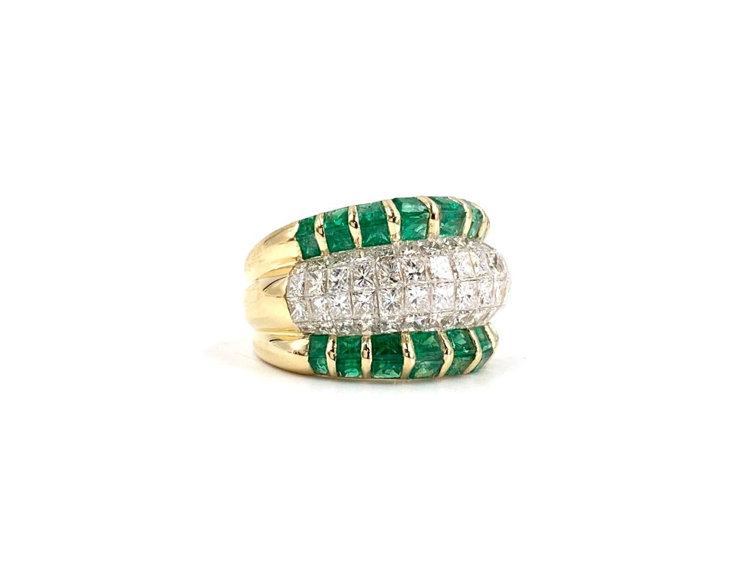 A very well made, uniquely designed 18 karat yellow gold wide ring featuring a center section adorned with 4 rows of expertly invisibly set seamless princess cut diamonds lined with two rows of princess cut emeralds on each side. Diamond total
