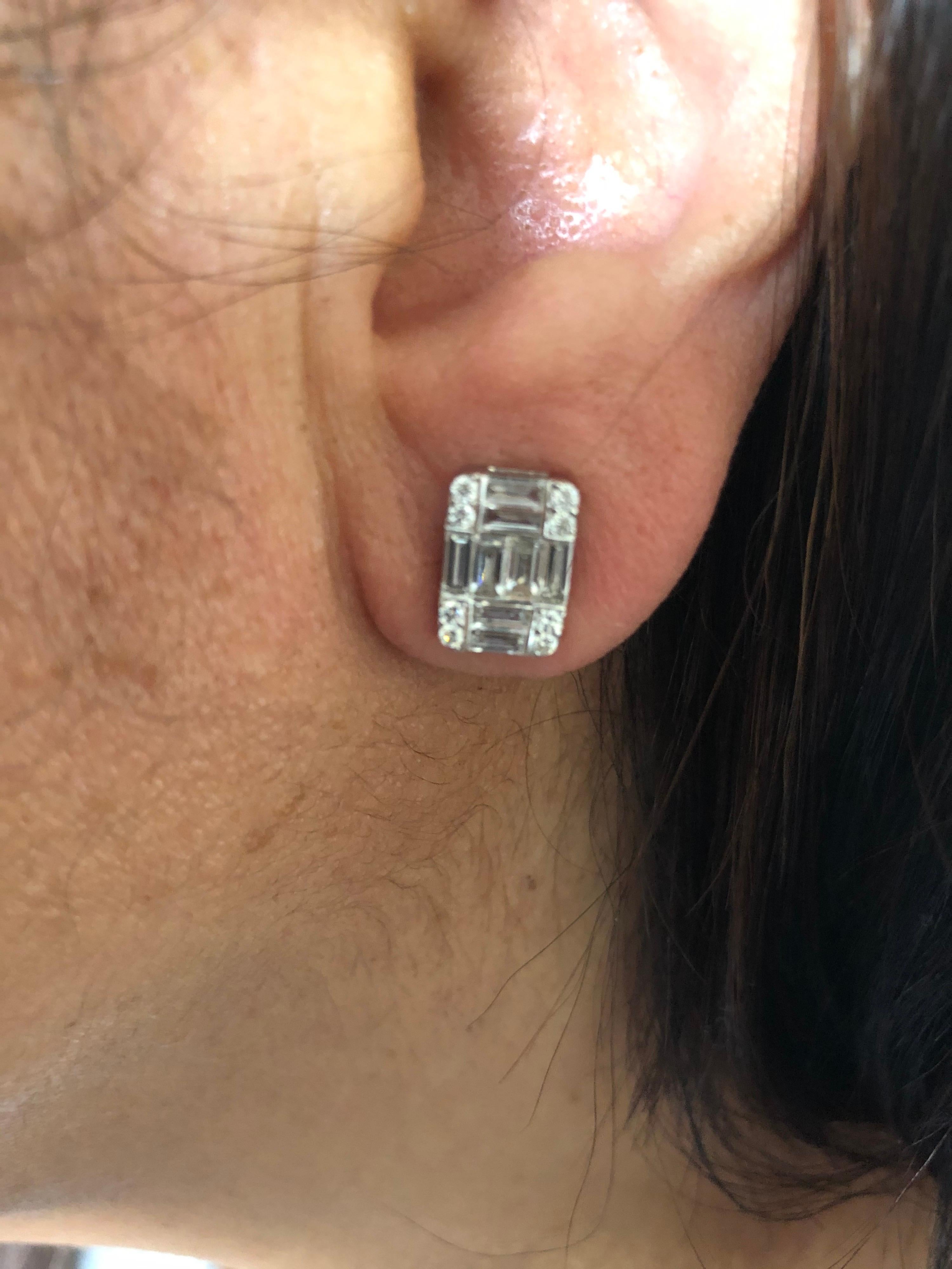 Emerald cut illusion earrings set in 18K white gold. The total carat weight of the earrings is 2.25 carats. The earrings are a cluster of baguette and round diamonds that create the illusion of a single emerald cut. The color of the stones are F,