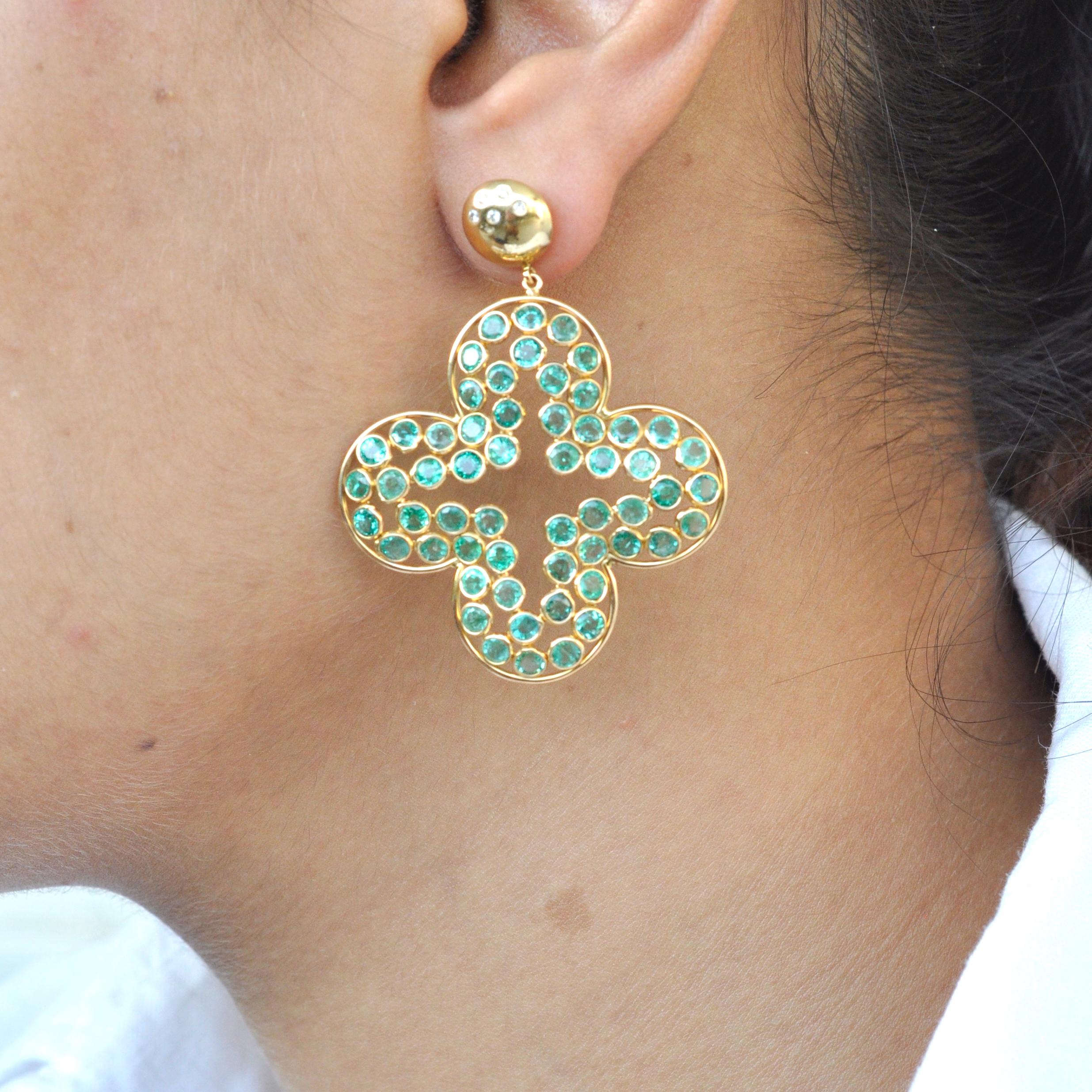 Statement Emerald clover dangle chandelier earrings, designed as a quatrefoil-shaped emerald cluster with bezel-set emerald surround suspended from a delicate pavé-set diamond, in 18k yellow gold. Post backs with secure hinged enclosure. 
Gross Wt.