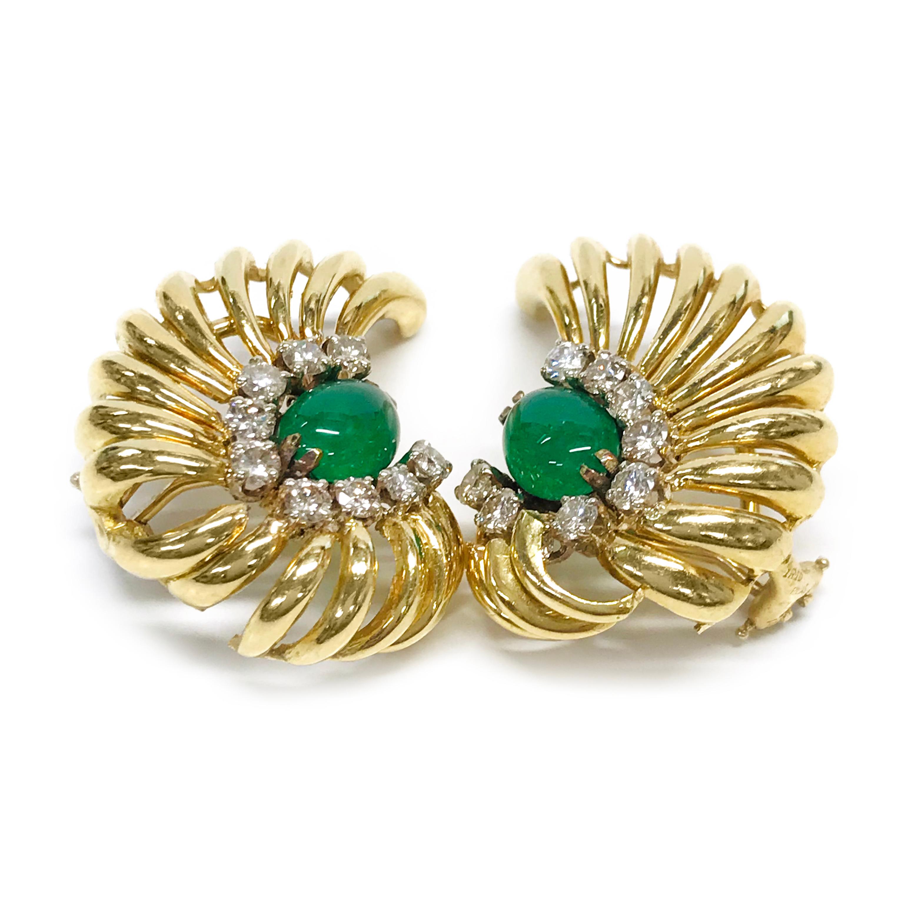 18 Karat Emerald Diamond Clip-on Earrings. Each earring features a 9mm x 6.5mm oval Emerald cabochon set with two double prongs and nine round prong-set diamonds around the bezel and gold wing-like swooshes that extend out. The diamonds are round