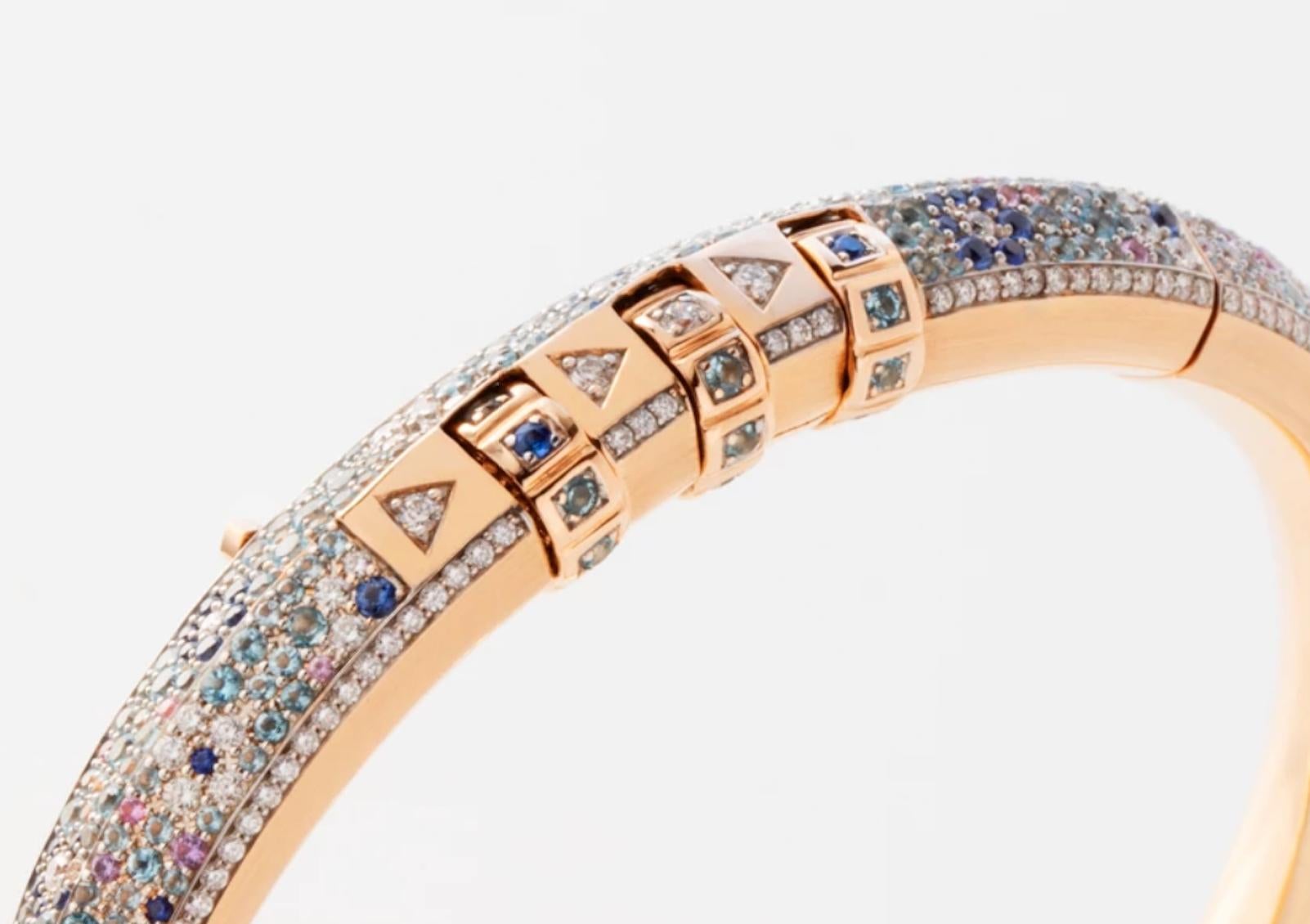 18 Karat Flower Code Minor Bracelet features a solid 18k Rose Gold bracelet with pave White Diamonds, Blue Sapphires, Pink Sapphires, Purple Amethyst, and Aquamarine that make up a flower pattern, with a custom code that opens and locks the bracelet