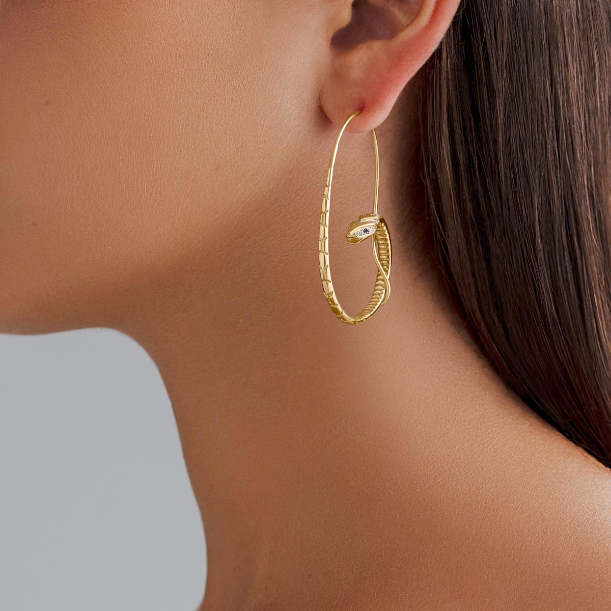 18 Karat Yellow Gold, 0.10 carat Sapphire and 0.34 carat Diamond Snake Hoop Earrings.

Symbolic of eternal love, these Snake Hoop Earrings have been handcrafted in our Cairo workshop. The tail of the Snake cleverly curls around the hoop to form the