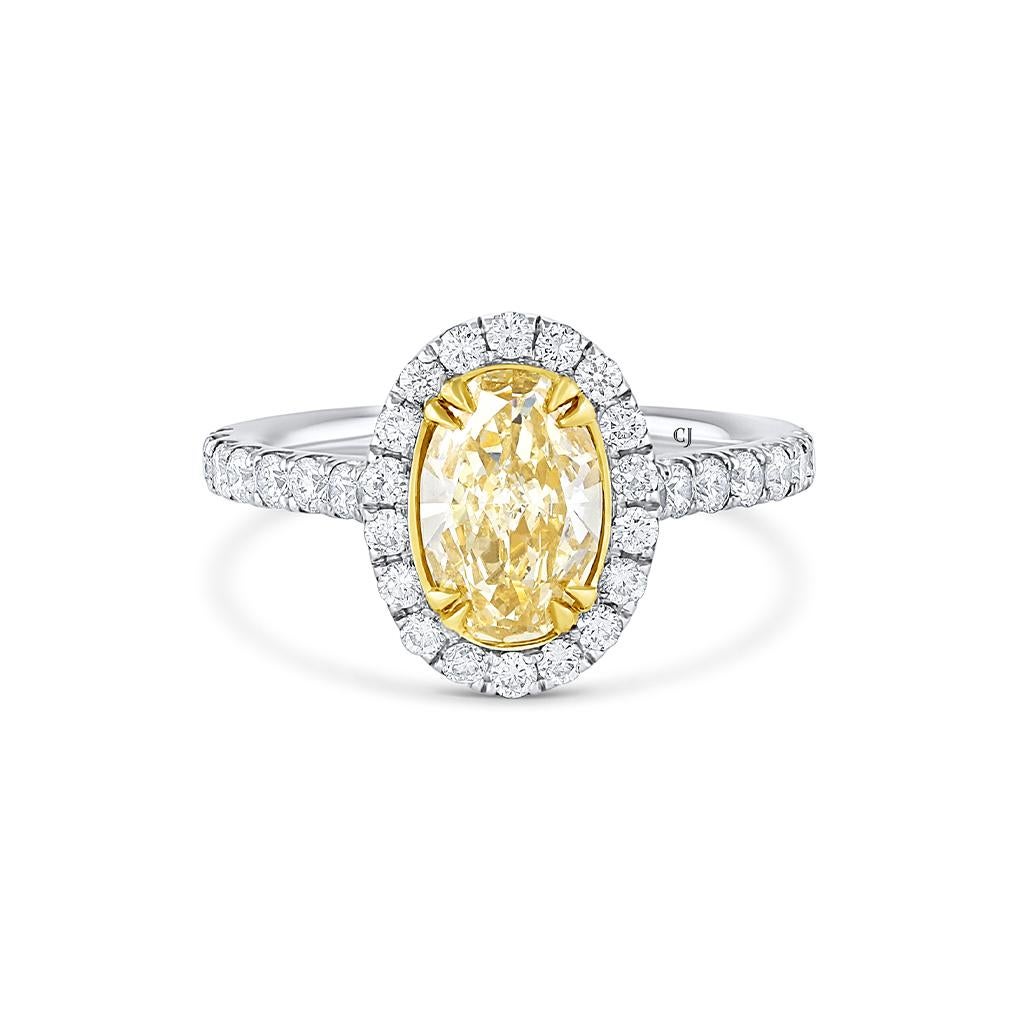 This elegant ring is crafted of 18 karat white gold and yellow gold. It features a oval 1.08 carat fancy yellow diamond and is surrounded by white diamonds weighing a total of 0.58 carats with F-H color and SI1 clarity. 
Size 6.