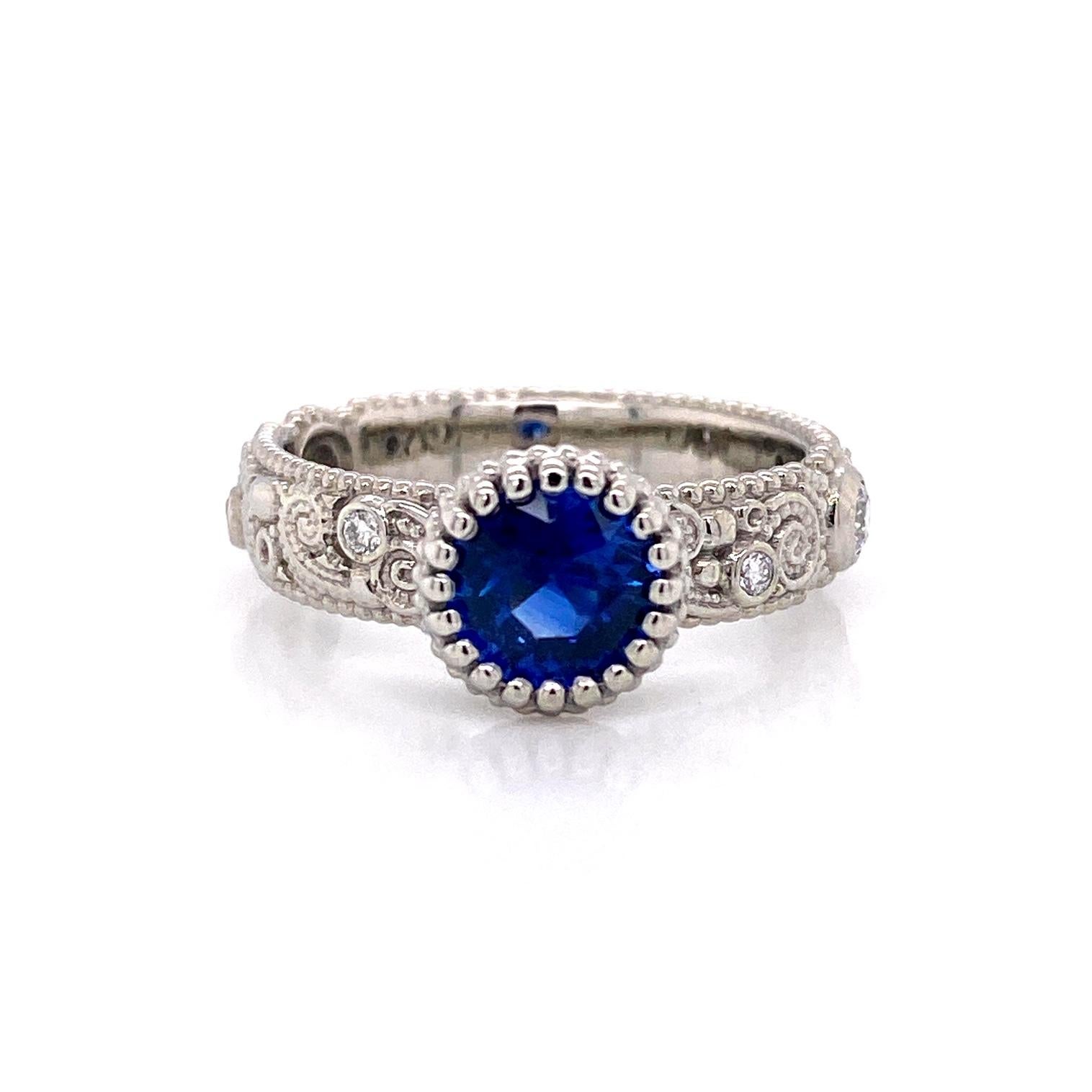 An 18k white gold llyn pattern ring set with one 1.09 carat round blue sapphire and F color VS clarity white diamonds,  (2) 2.5mm for .12 carat weight, and (6) 1.5mm for .09 carat weight. Ring size 7. This ring was made and designed by llyn strong.