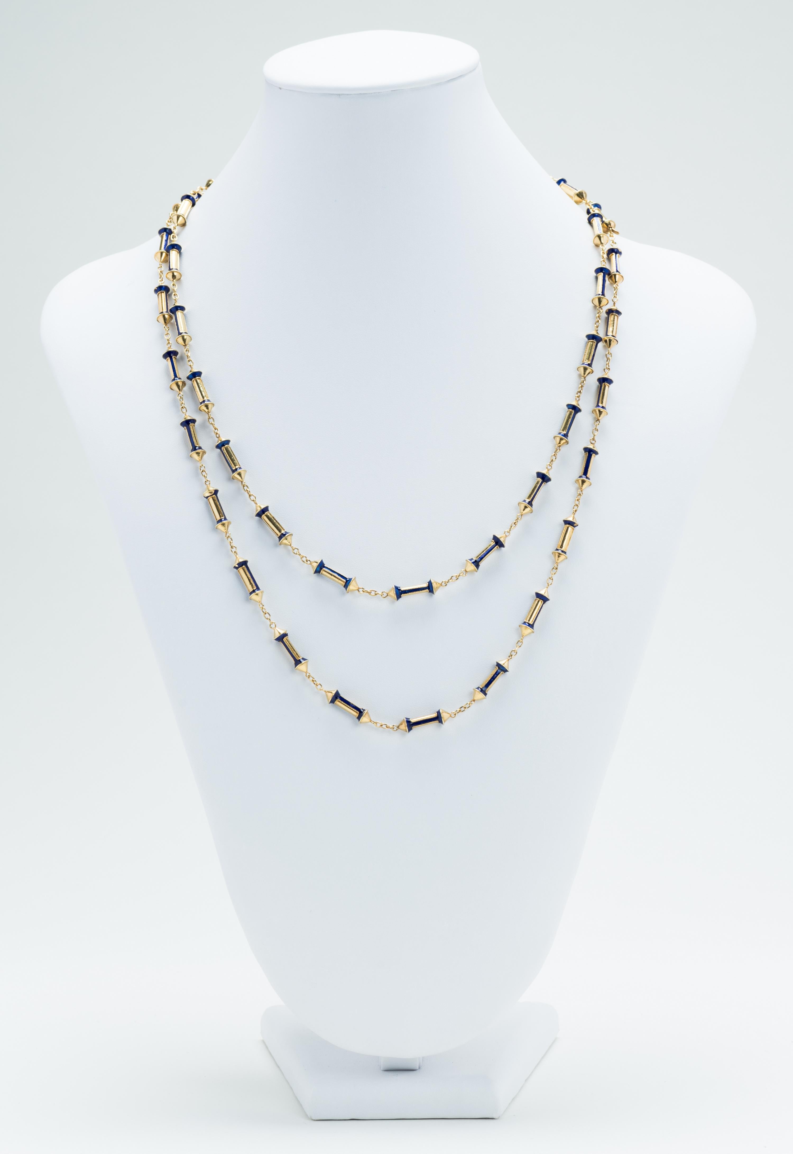 The 18 karat gold and blue enamel necklace has tubular links inset with blue enamel.  Each link is connected by a small oval linked chain.  The necklace detaches and becomes two 11 1/2” necklaces.  There is an 18 karat gold stamp on each clasp.